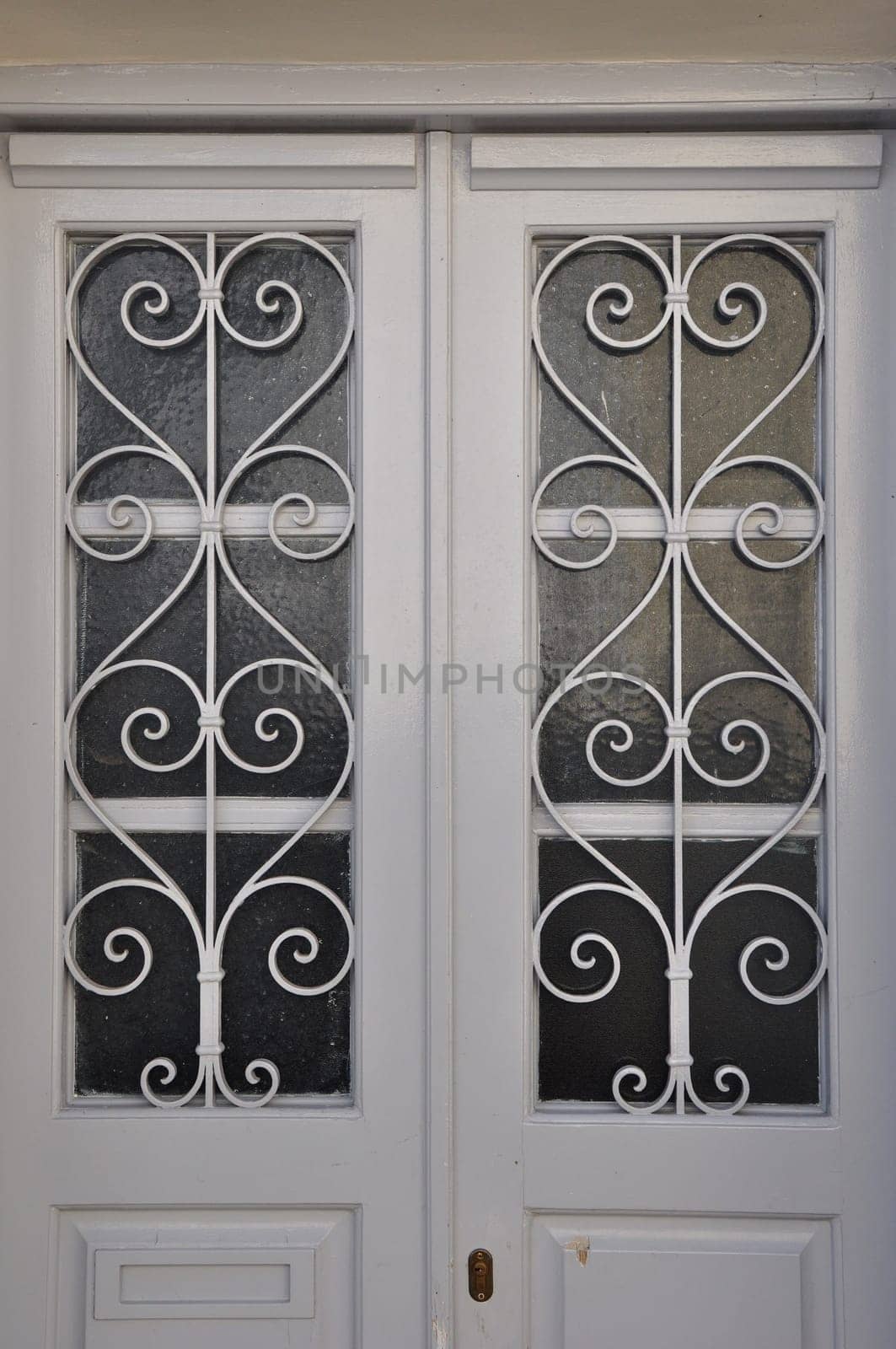 White wooden door frame with glass lite and vintage metal pattern.
