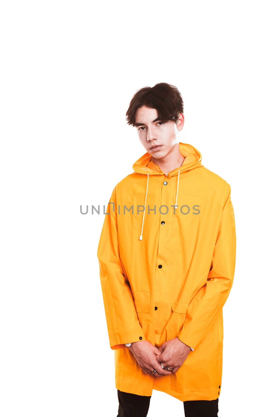 portrait of a teen guy in a yellow raincoat brunette in the studio.