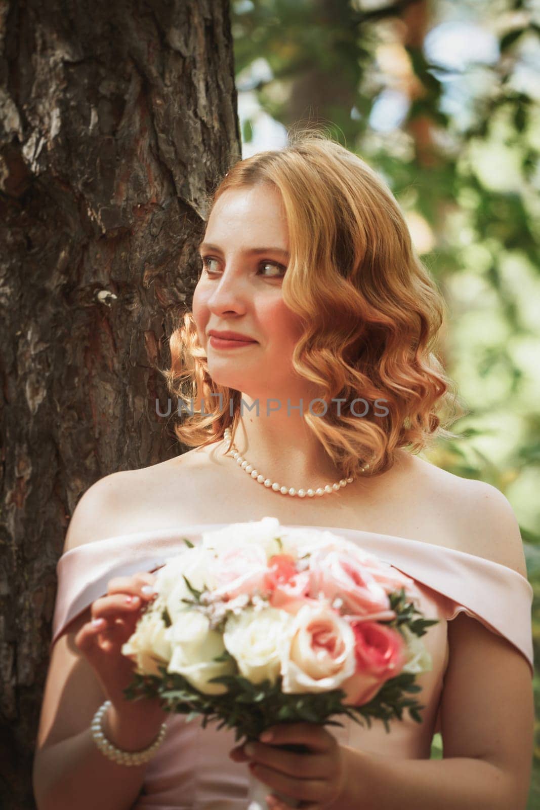 portrait of a beautiful bride standing near a tree.