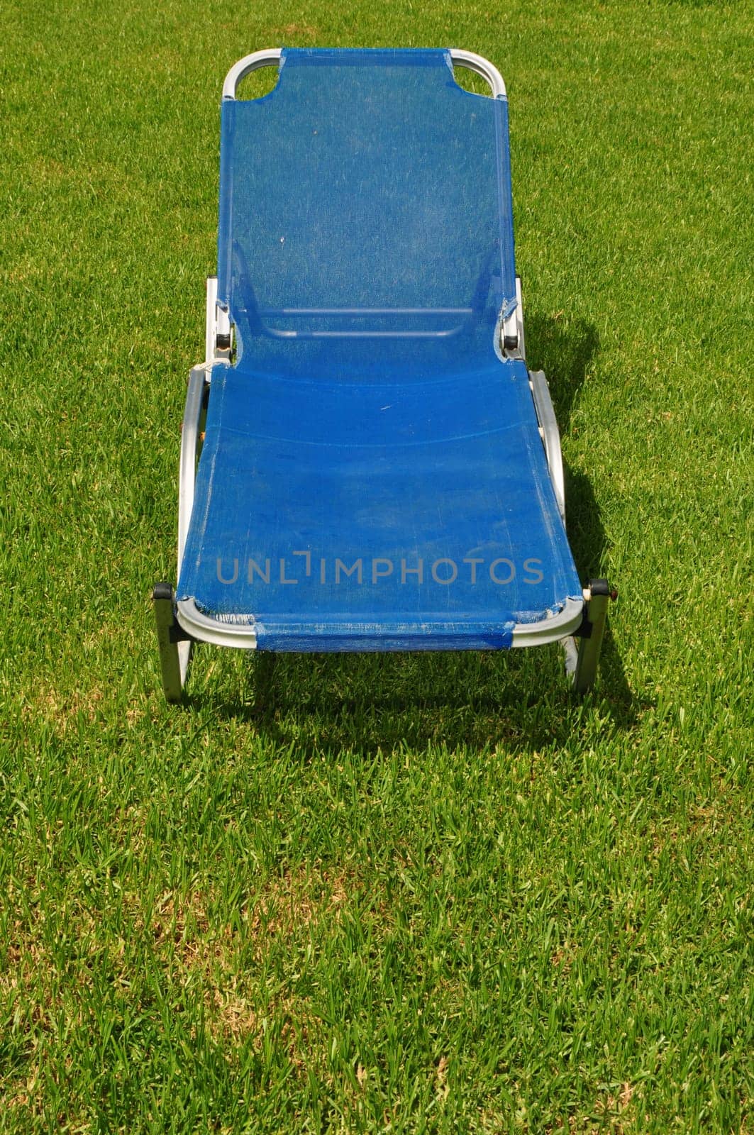Reclining lawn chair on green grass background. Garden furniture.