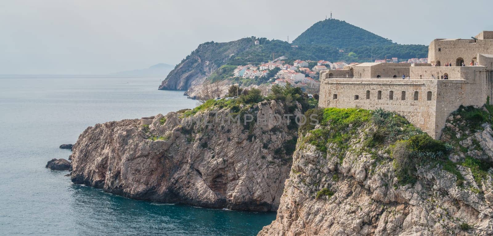 Dubrovnik, Croatia - April 2018 : Rocky coast alongside Dubrovnik Old Town massive defence walls of fortress Bokar