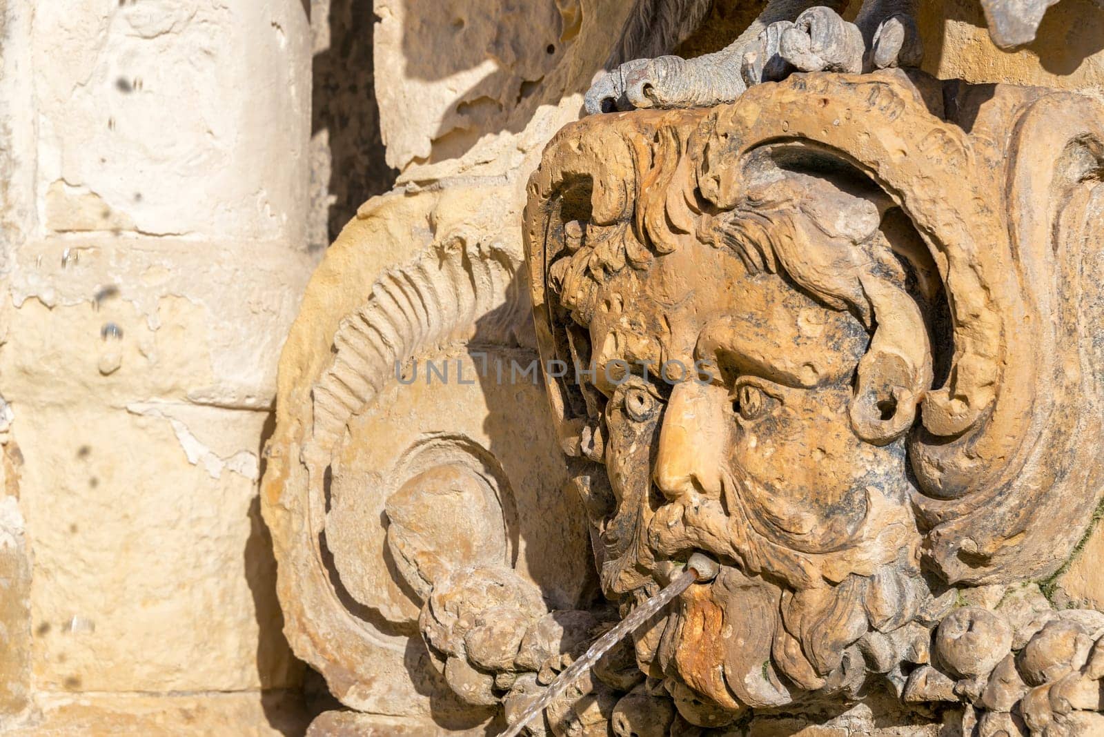 Closeup of a fountain in the shape of a face on St. Georges Square in Valletta, Malta