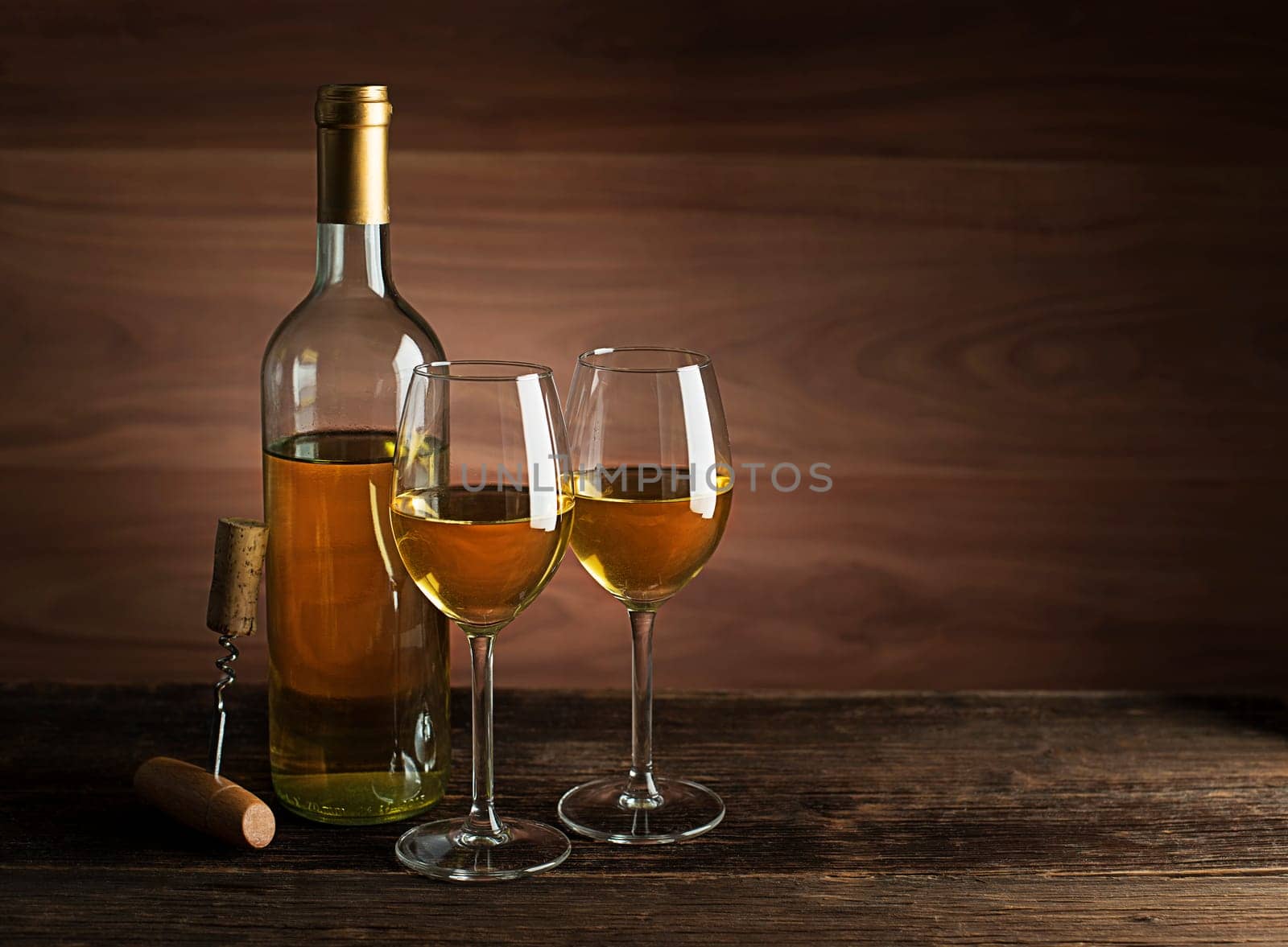 Bottle of white wine with wine glasses on wooden background