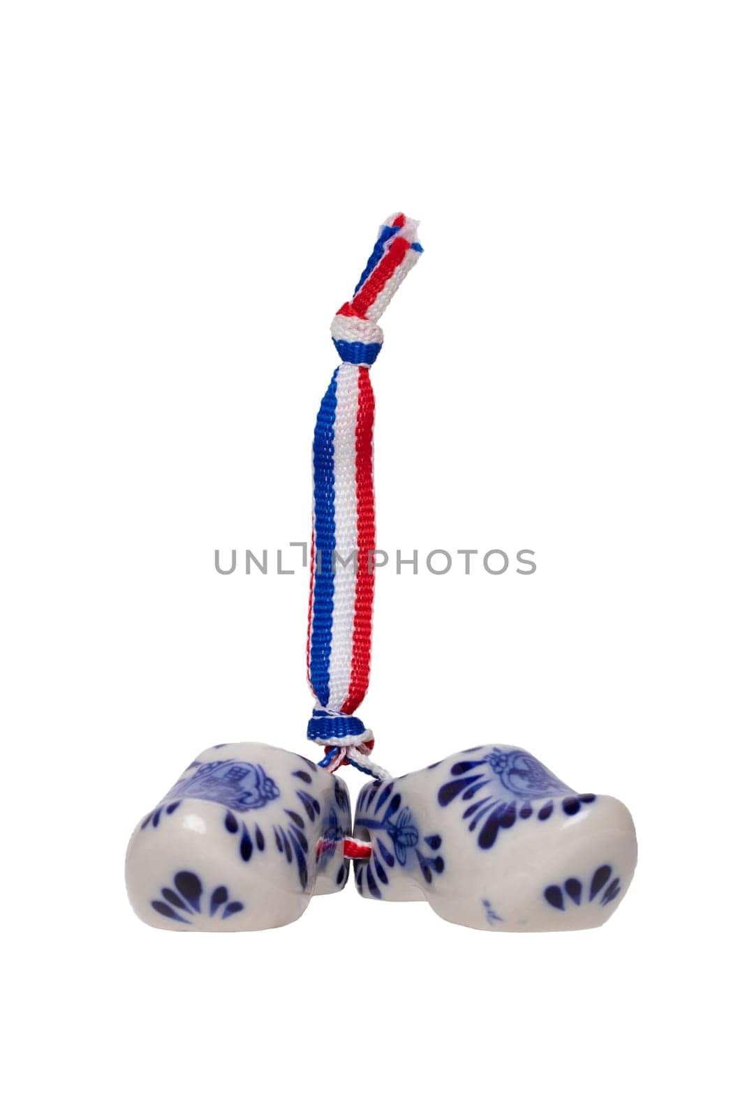 Holland wooden clogs. A pair of traditional dutch porcelain shoes with a ribbon flag isolated on a white background. Souvenir from Amsterdam.
