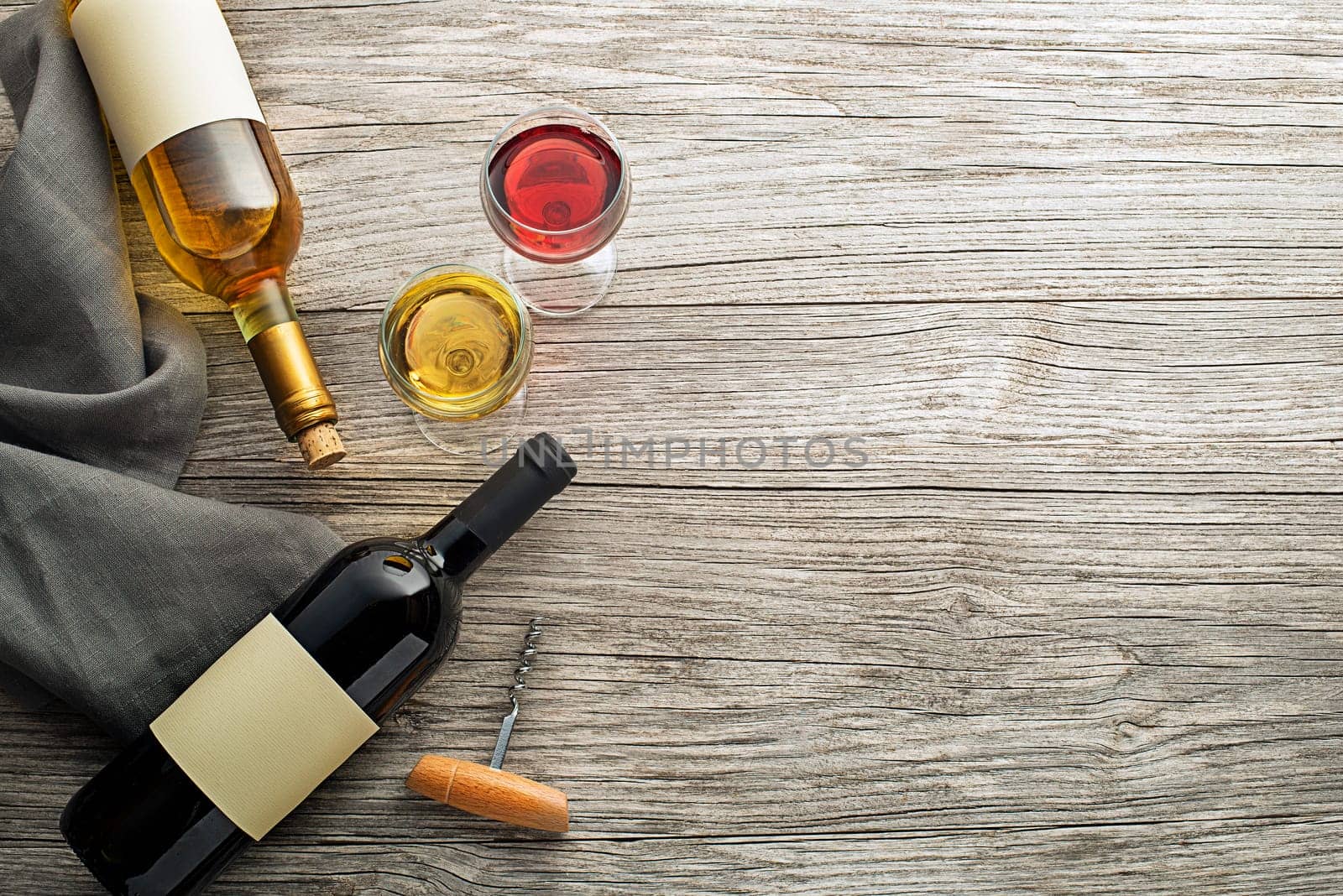 Glass and bottle of red and white wine on wooden background. Wine bottle mockup. Top view