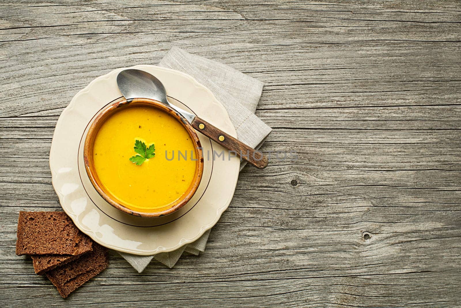 Healthy pumpkin and turmeric or curcuma cream soup on wooden background