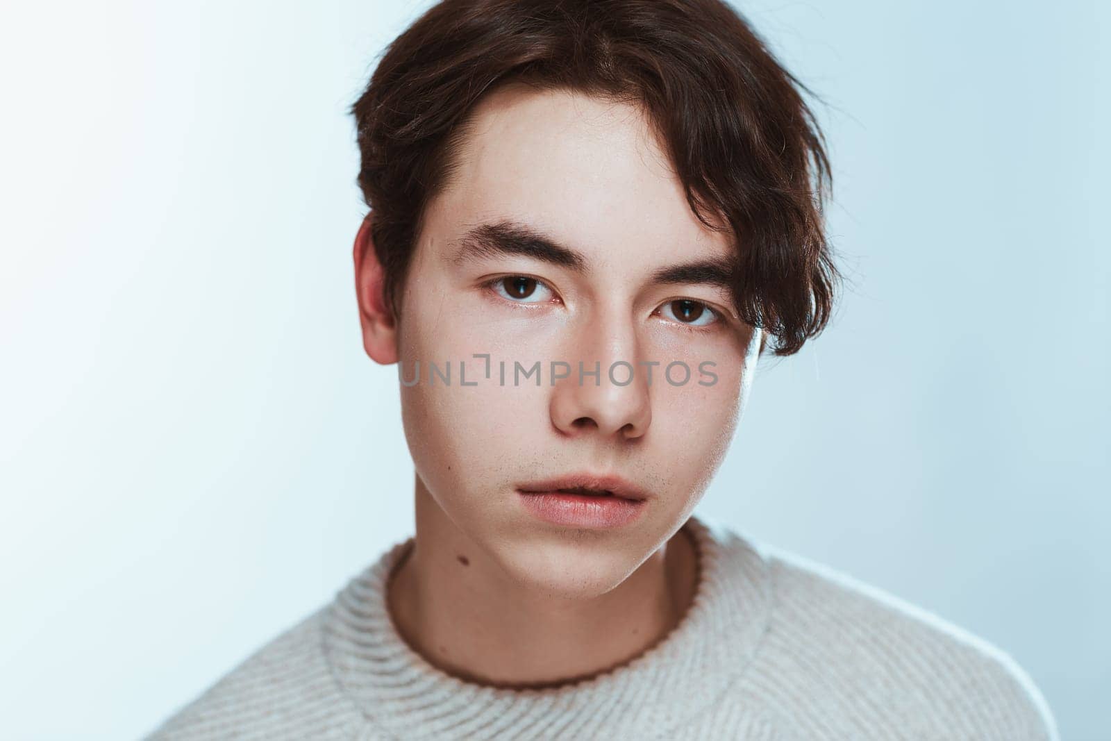Studio portrait young man in grey sweater on white background.