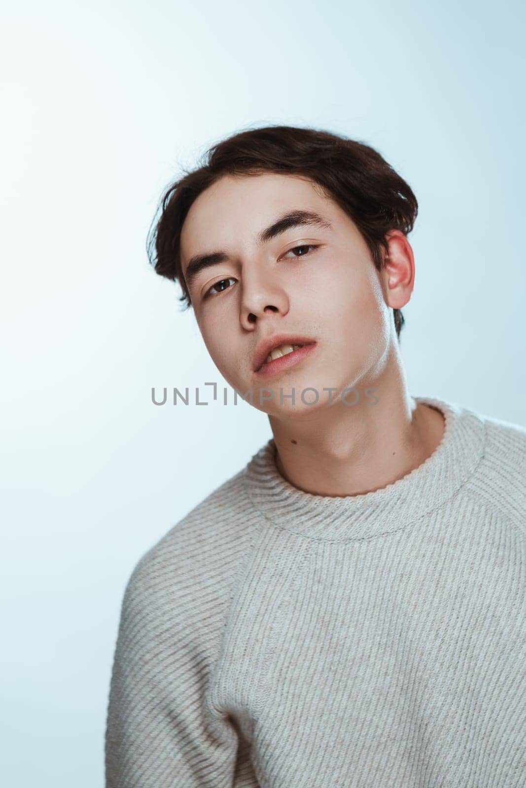 Studio portrait young man in grey sweater on white background.