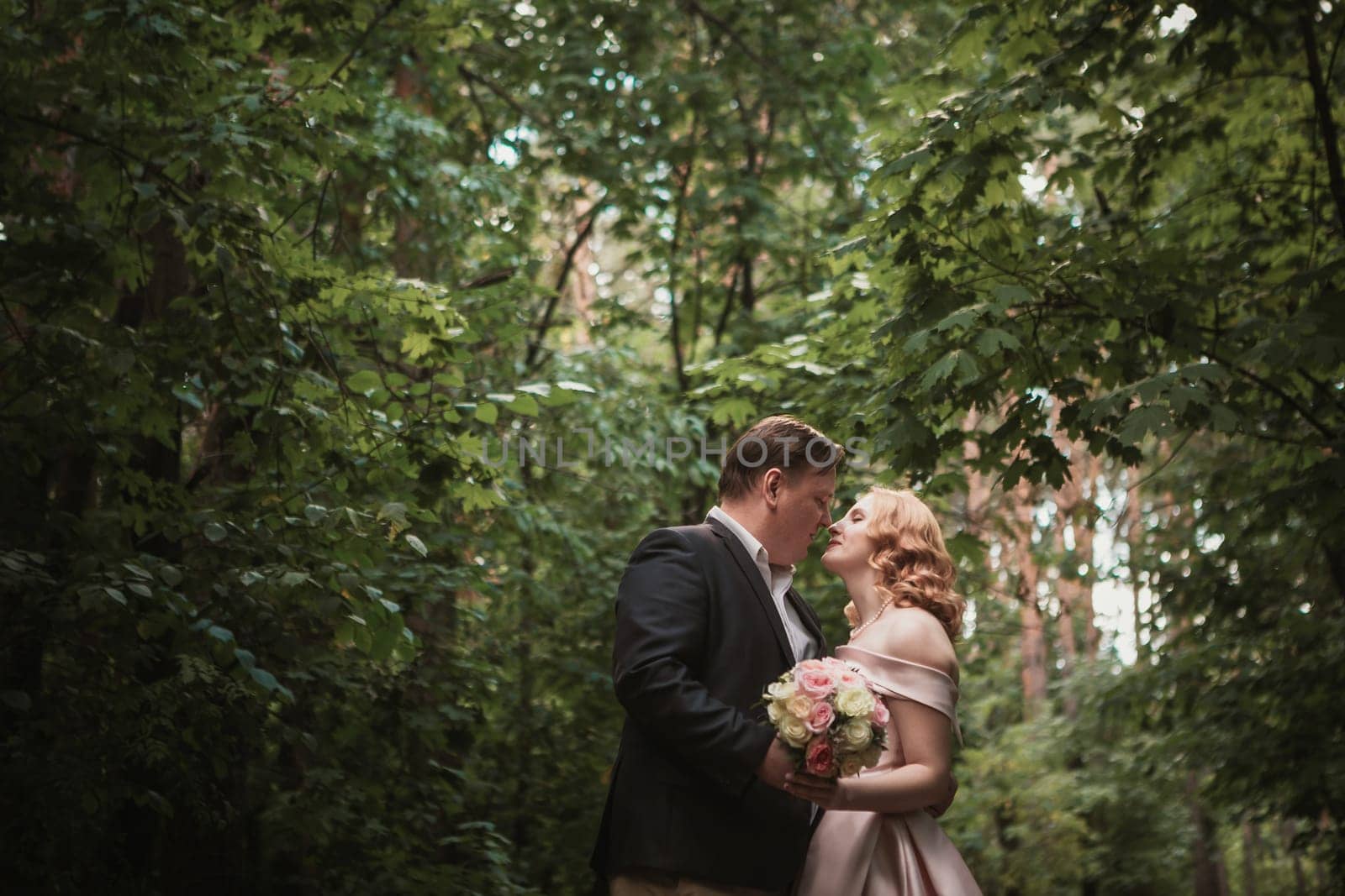 bride and groom dancing in the forest background and sunlight.