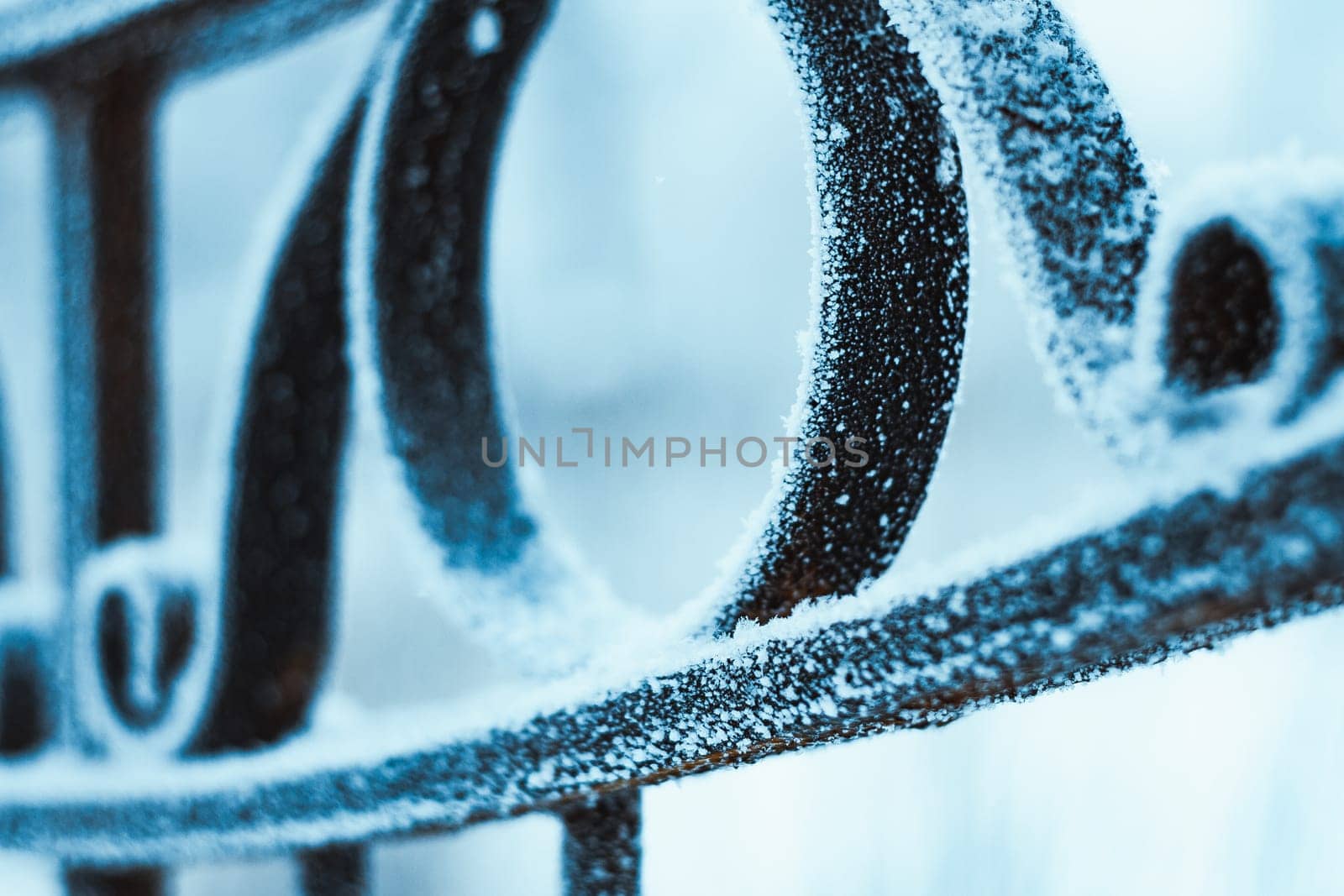 metal fence in hoarfrost on a blurred background.