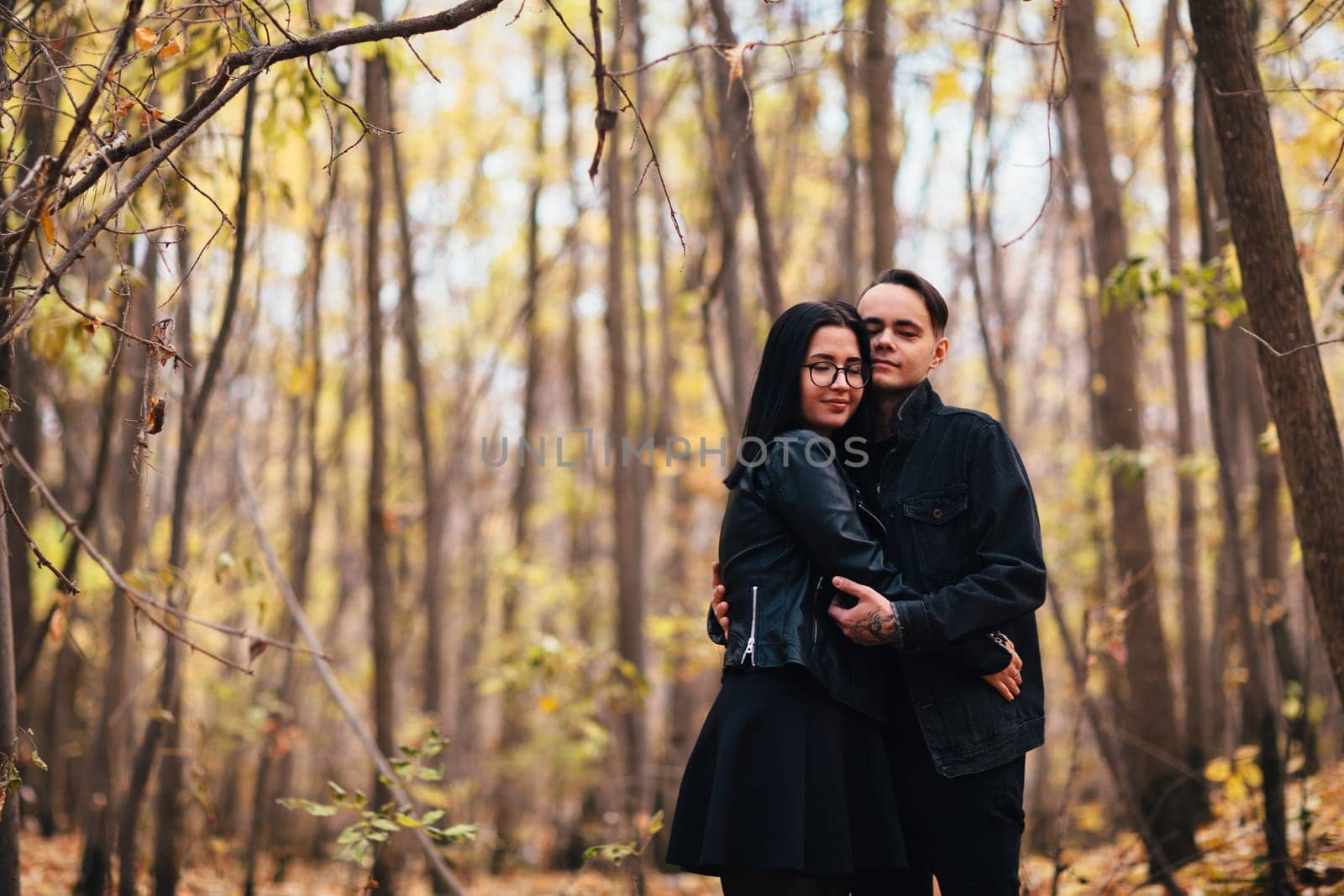 The girl and the guy are walking in the autumn forest.