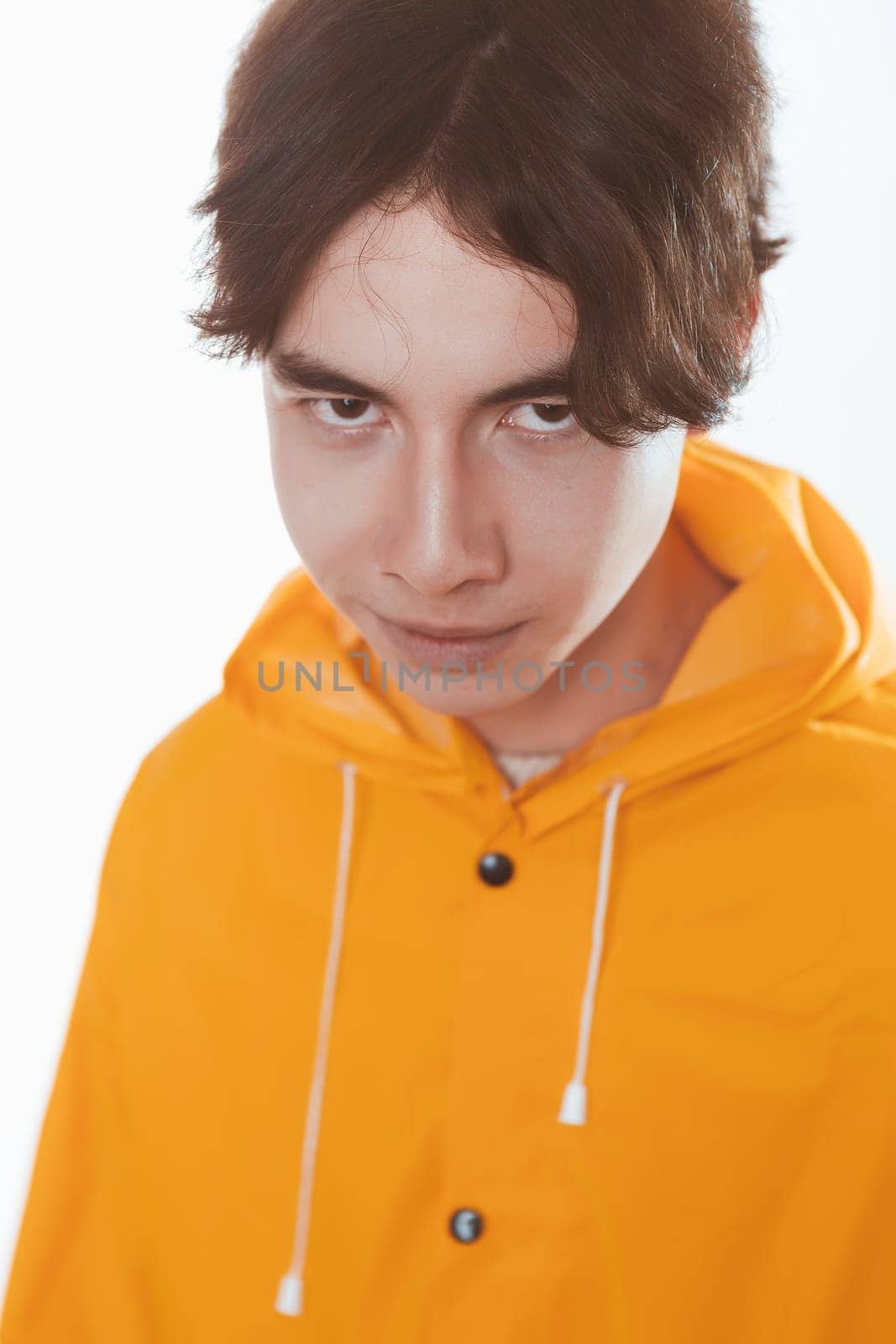 portrait of a teen guy in a yellow raincoat brunette in the studio.
