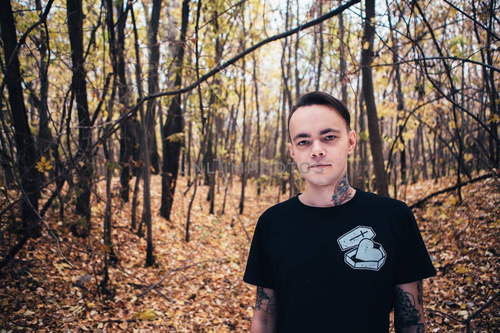 portrait of a man with tattoo in the autumn forest.