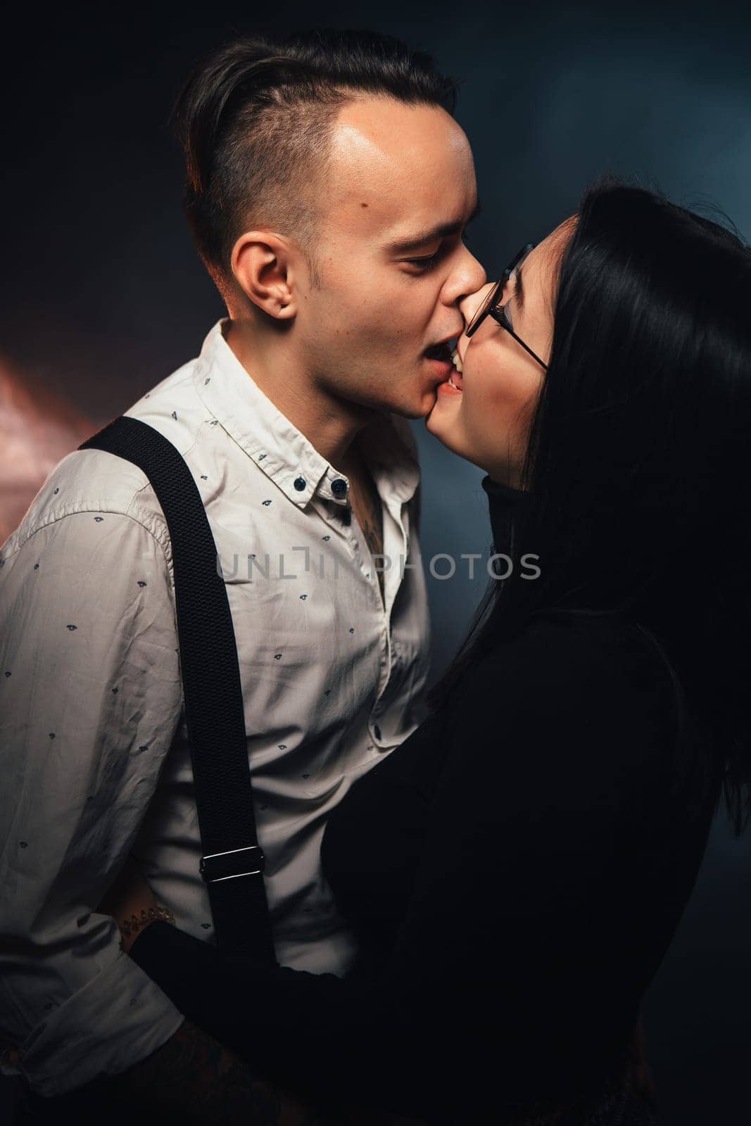 Couple in fashionable clothes on a dark background with smoke.