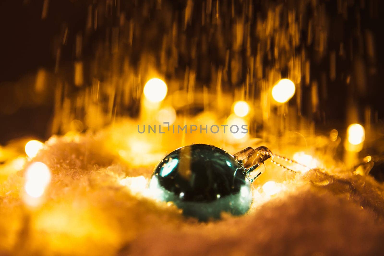 blue Christmas ball and luminous garland on the snow.