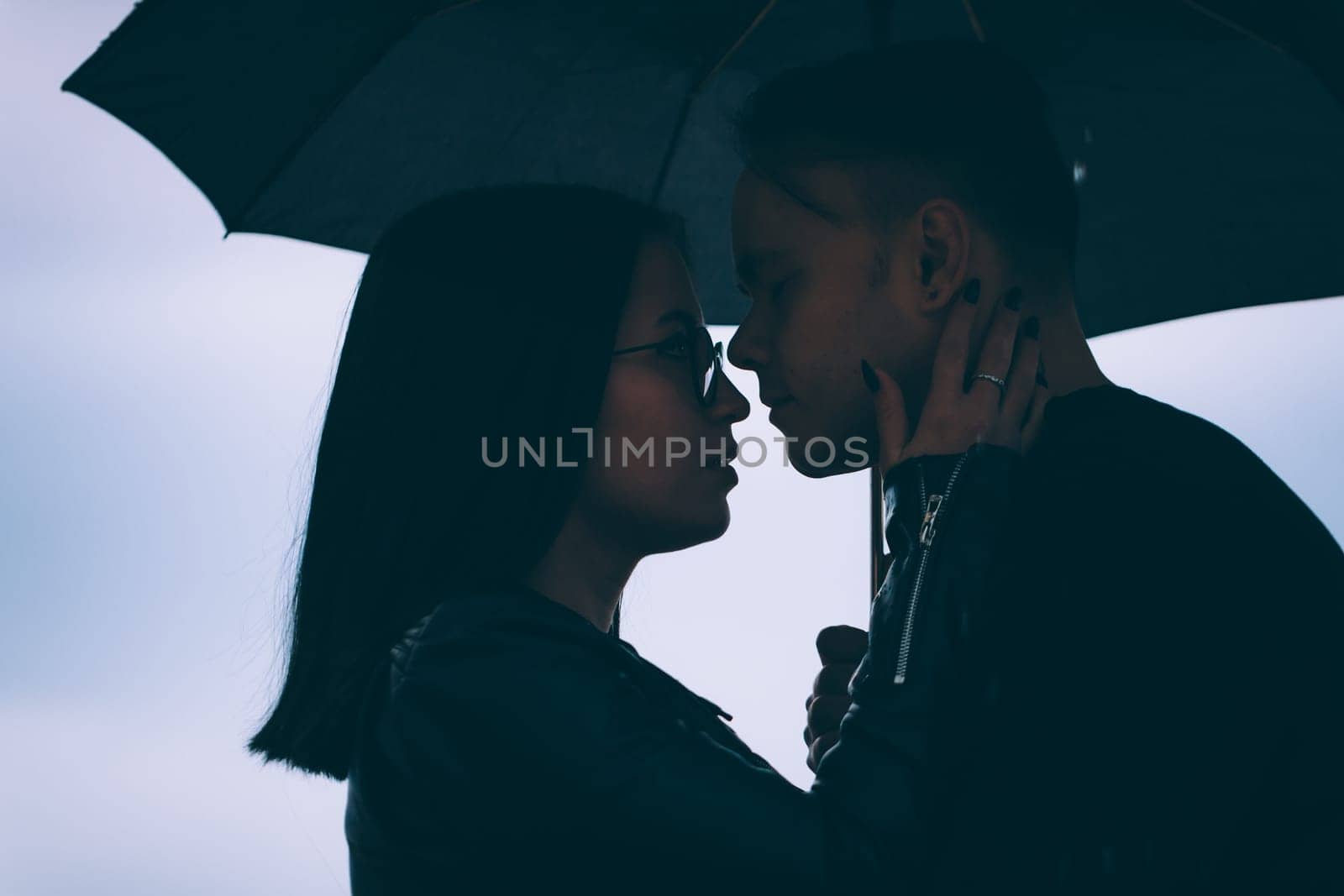 young man and woman under an umbrella and rain.