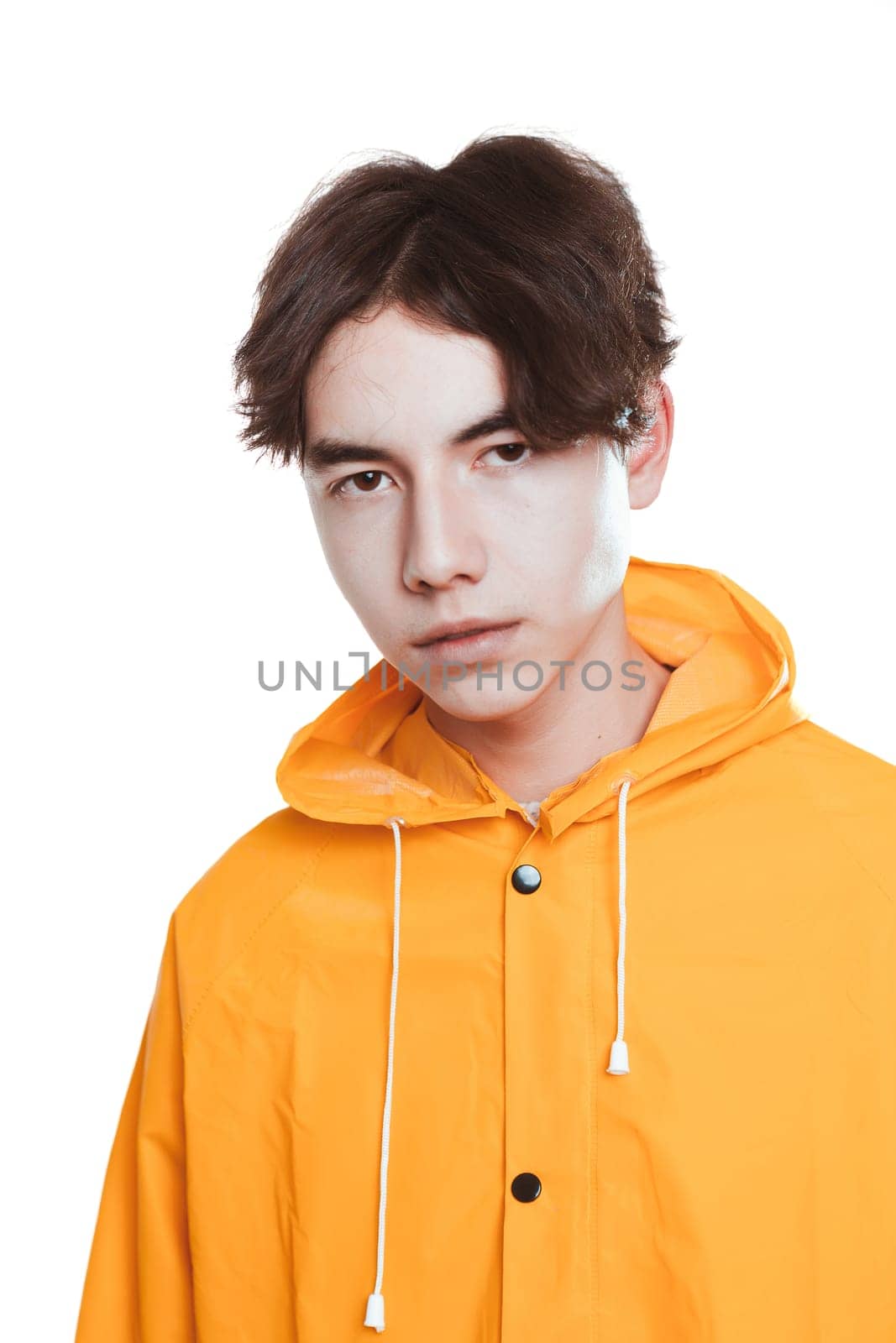 portrait of a teen guy in a yellow raincoat brunette in the studio.