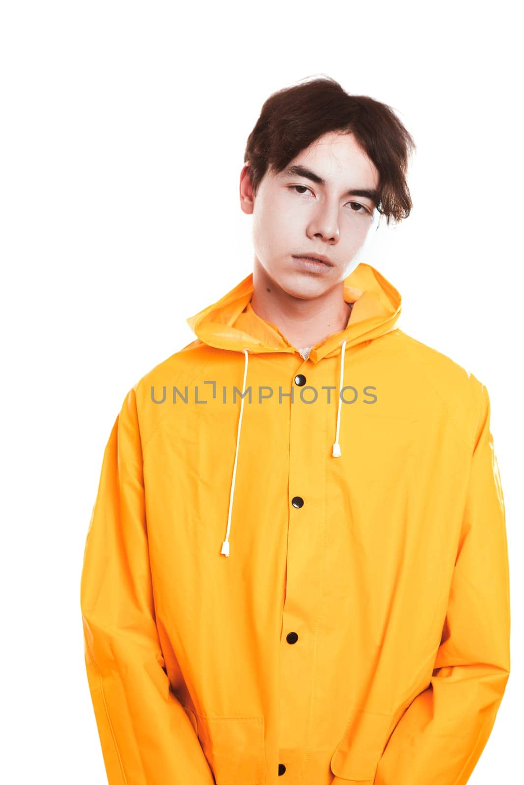 portrait of a teen guy in a yellow raincoat brunette in the studio.