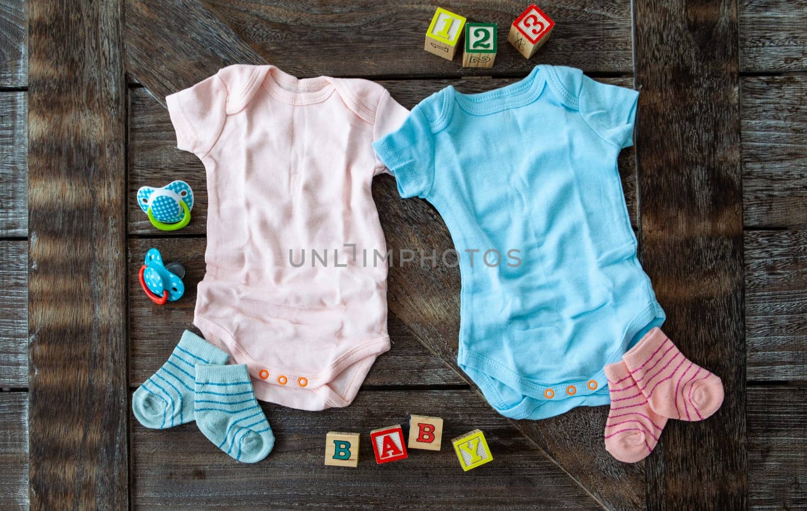 Baby clothing in pink and blue on rustic wooden background