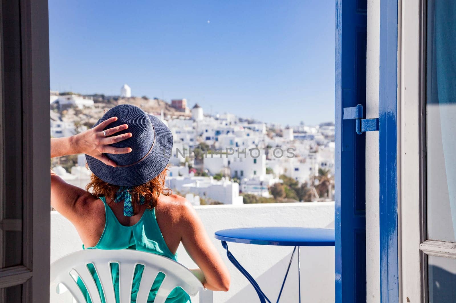 woman enjoying mykonos town view from terrace, Greece - summer holiday