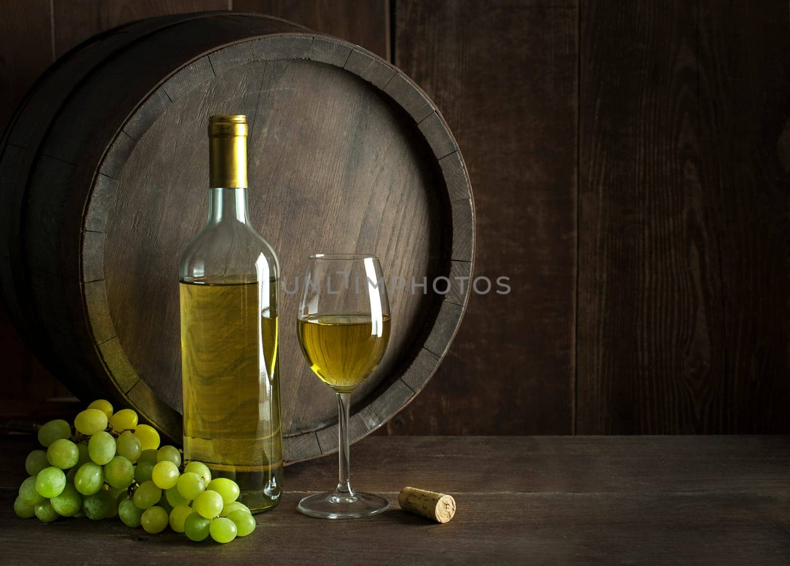 Bottle of white wine with cork. Glass of wine with barrel background