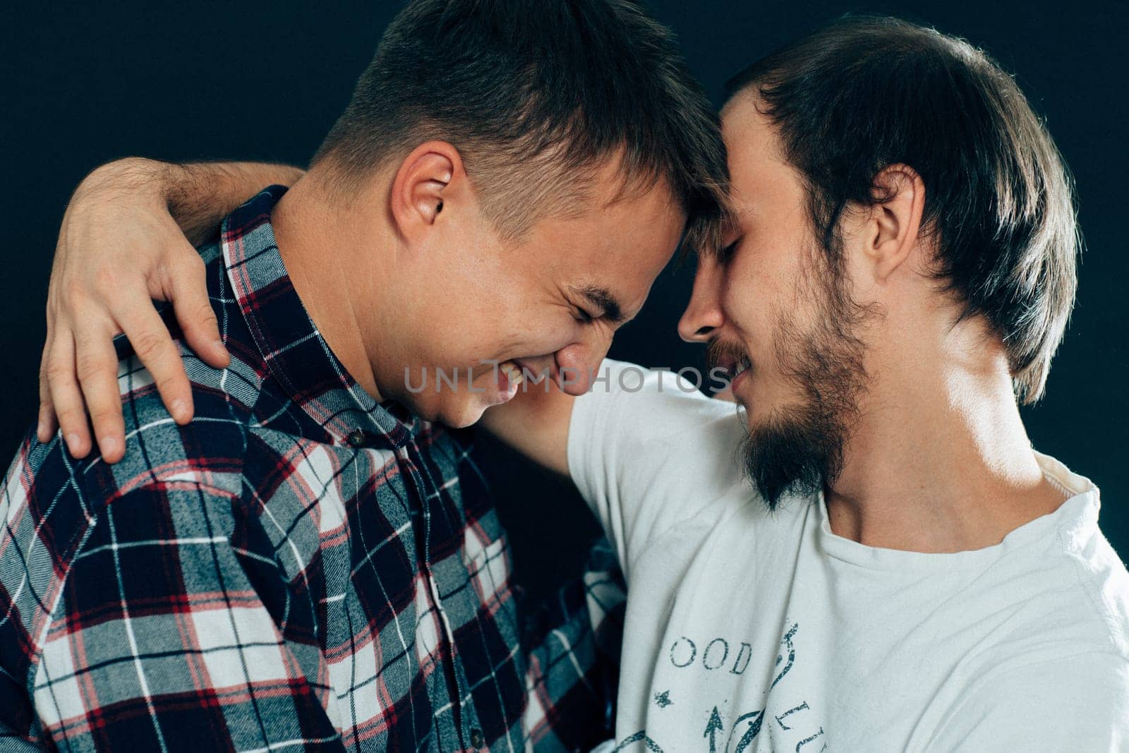 two guys hugging on a dark background.