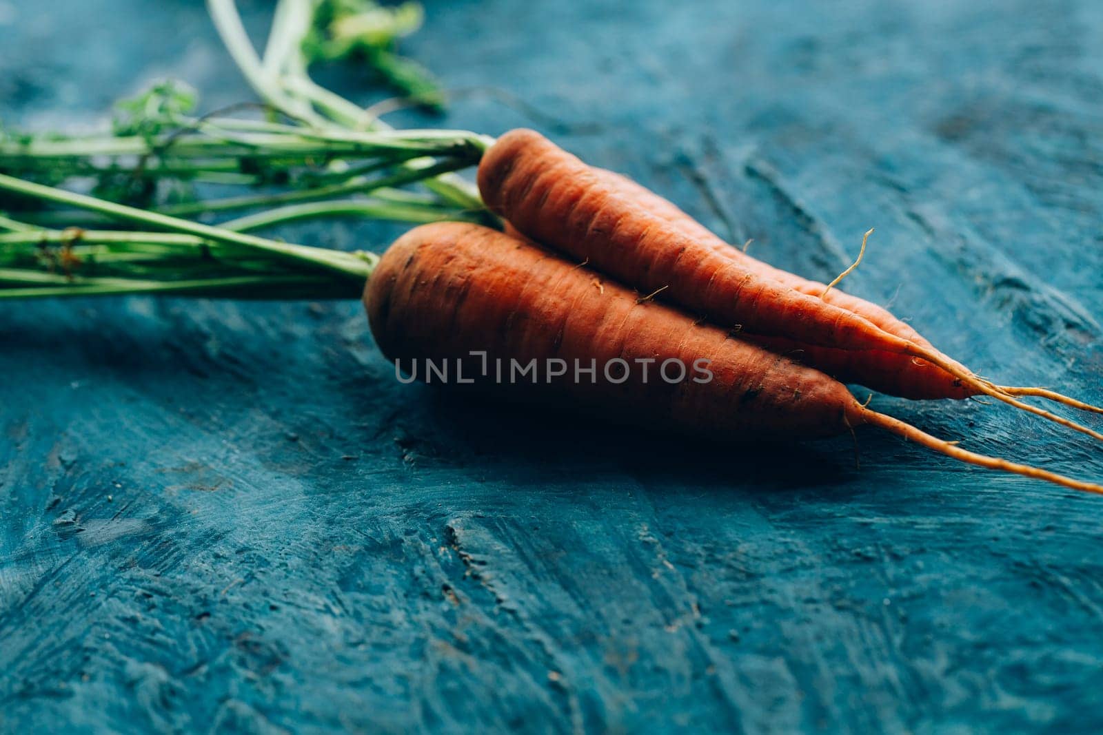 Fresh carrots on a blue wooden background.