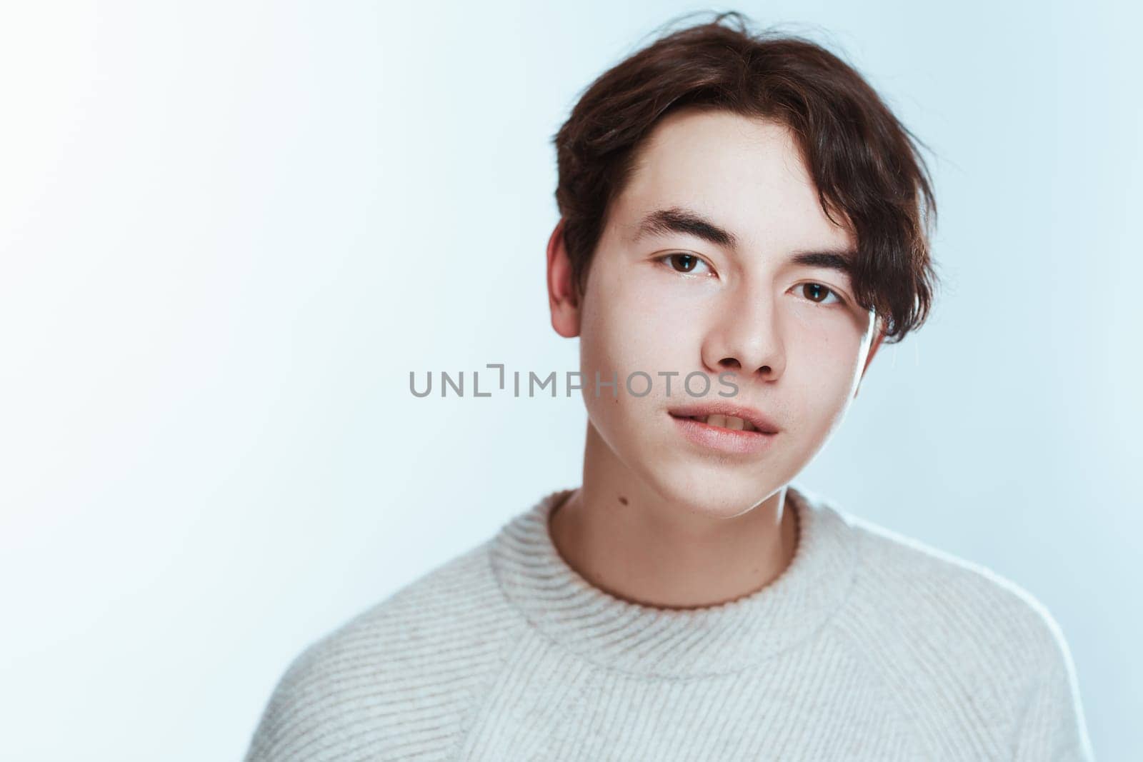portrait of a teenager brunette guy in a studio.