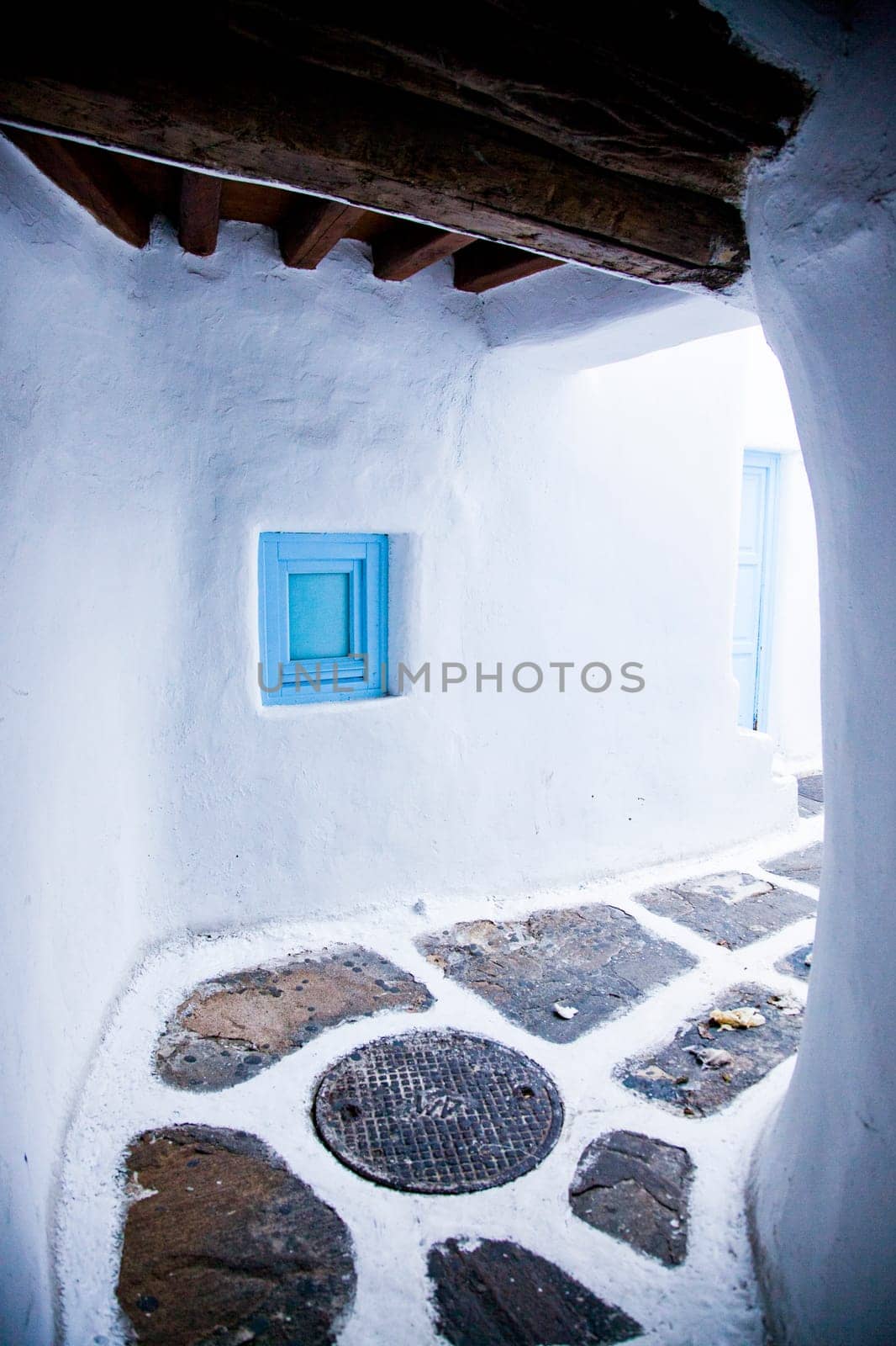 traditional narrow street in Mykonos with blue doors and white walls
