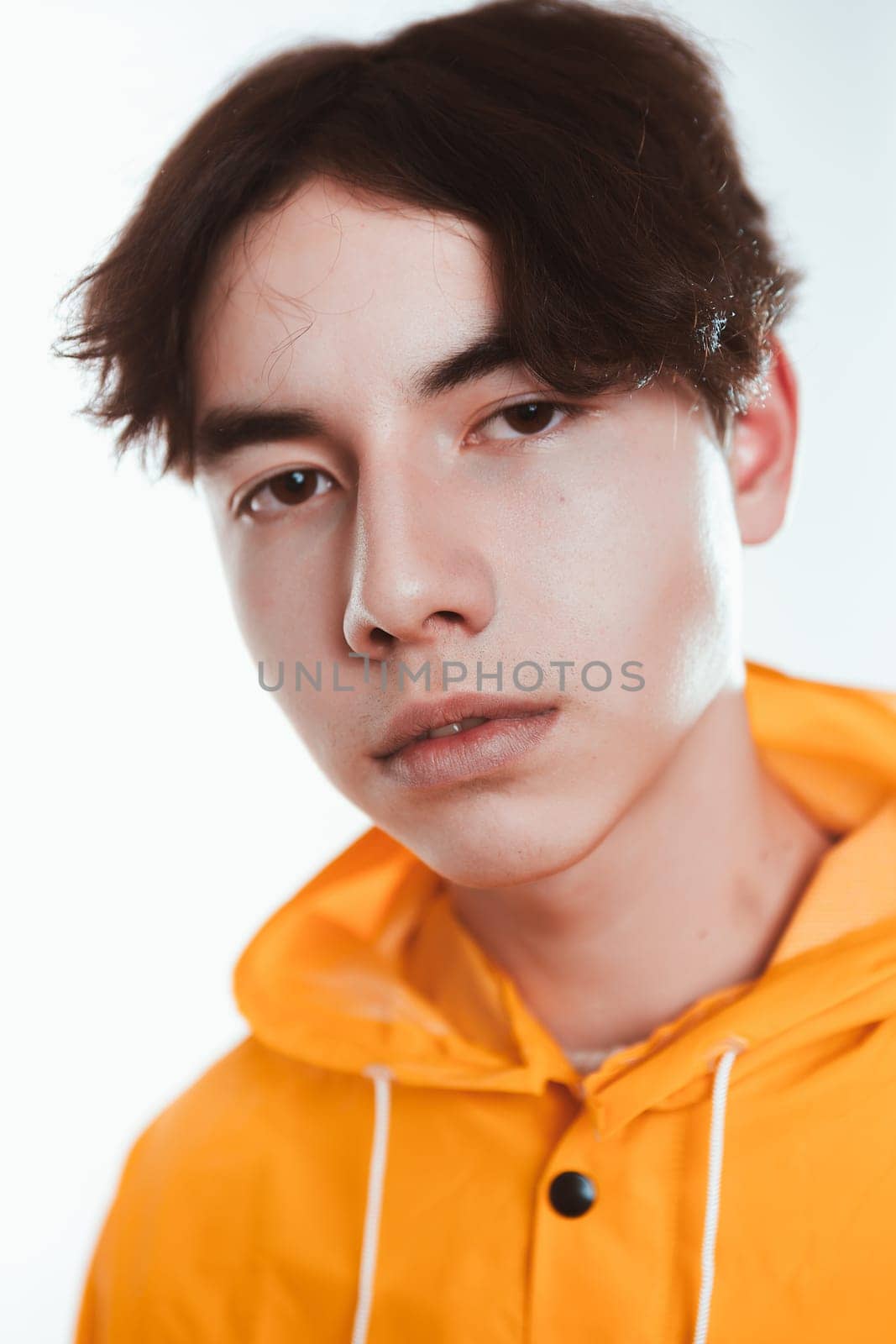 portrait of a teen guy in a yellow raincoat brunette in the studio.