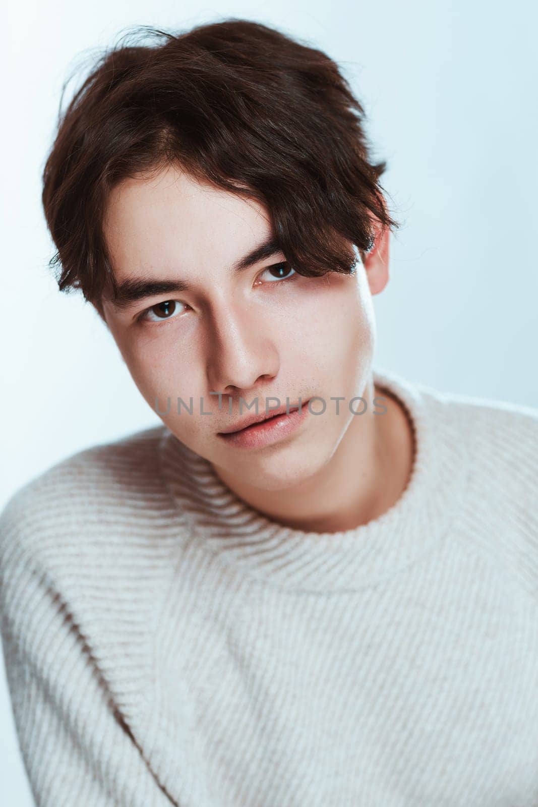 Studio portrait young man in grey sweater on white background.