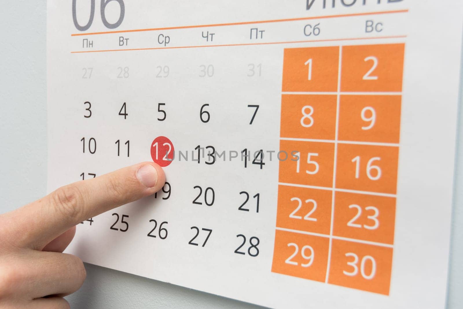 Finger points to a holiday in the wall calendar