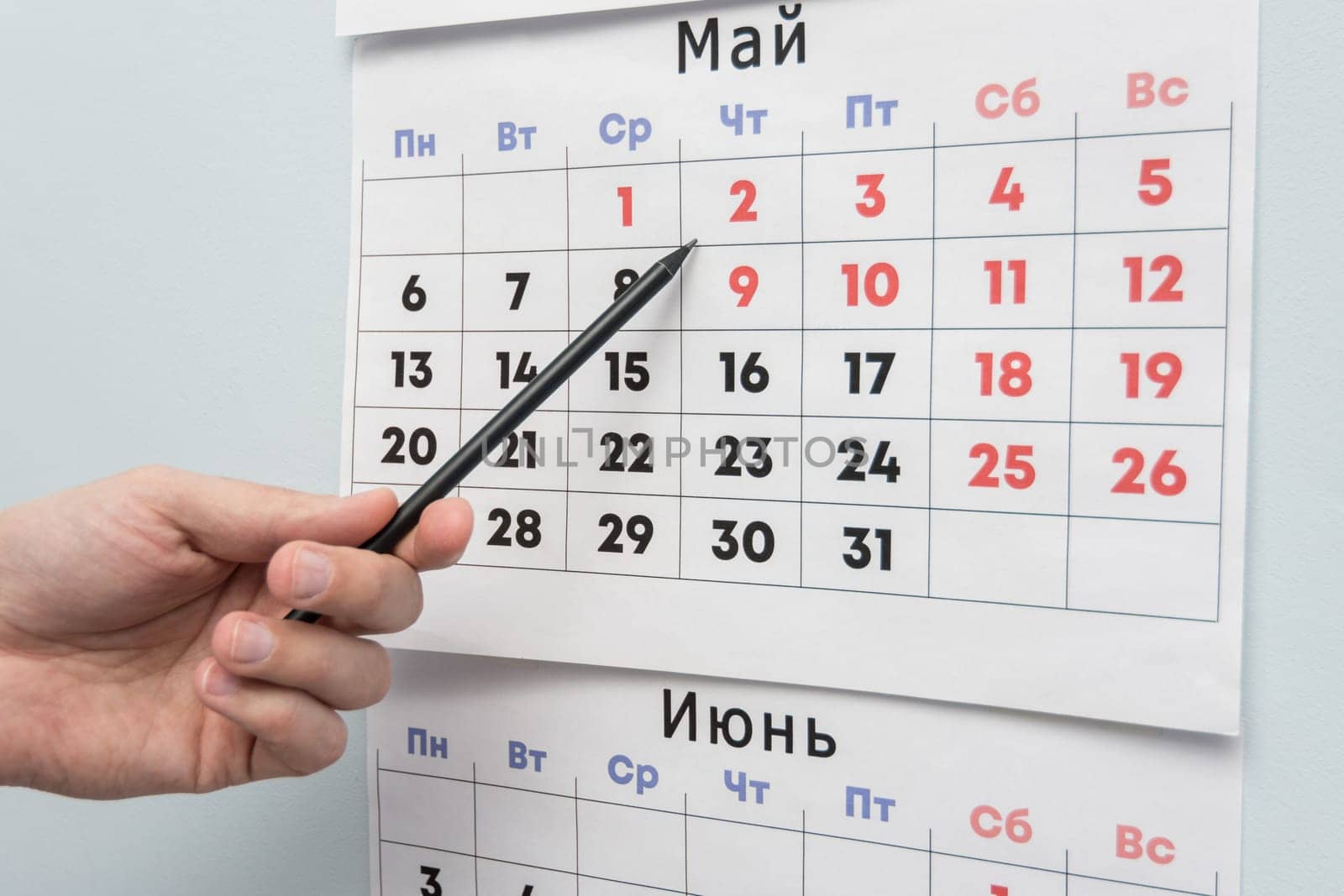 Pencil hand indicates long weekends and holidays on a wall calendar