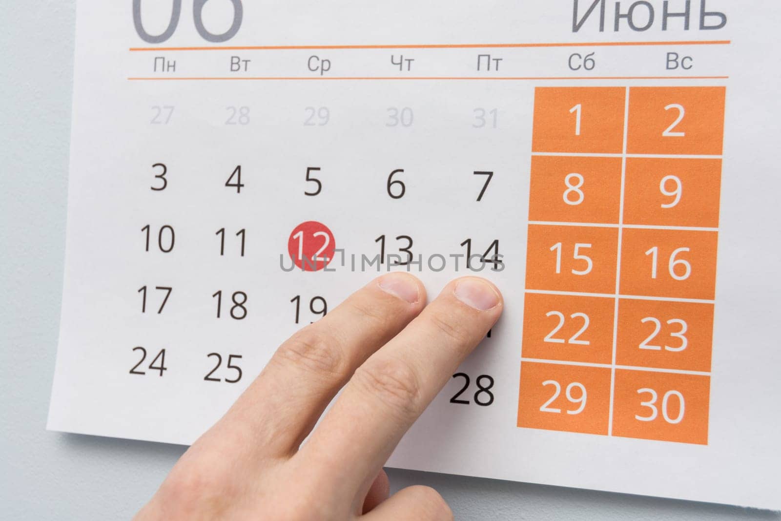 Fingers point to June 13 and 14 in the wall calendar