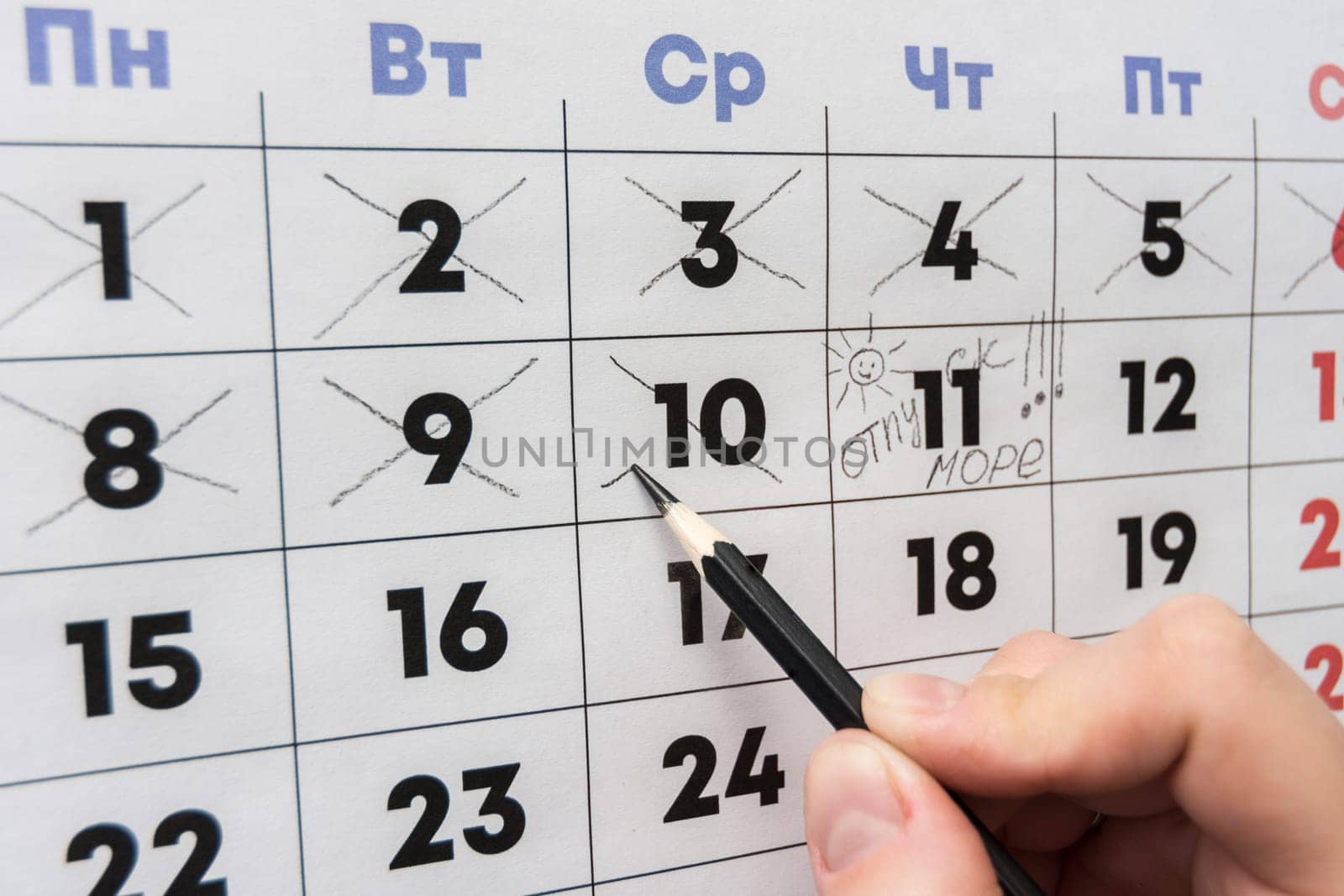 Hand cross out the last working day with a pencil in the calendar before the holiday
