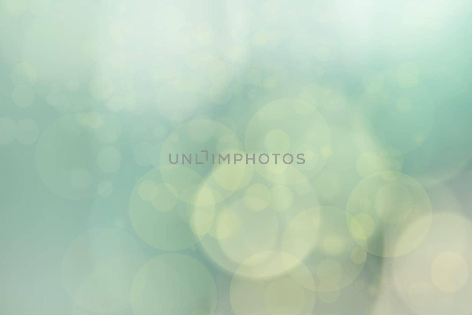 Abstract blurred light green pastel background texture with bright bokeh circles.