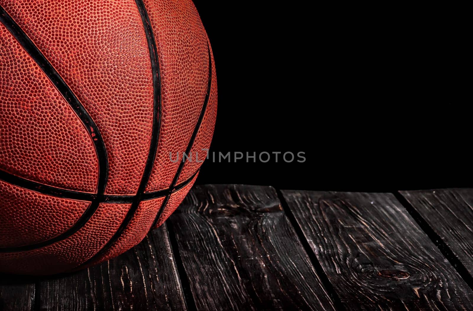 Closeup old ball on a wooden floor. Black background.