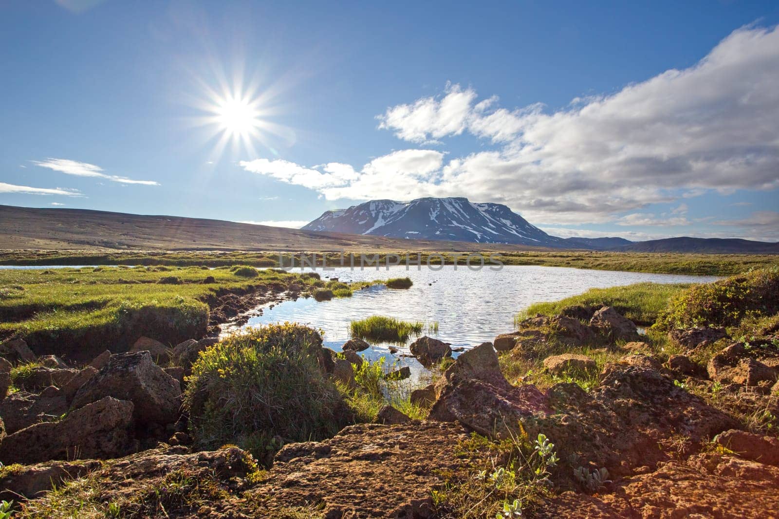 Icelandic summer nature scenery with sun, lake and mountain. Nordic sunny landscape with bright colors.