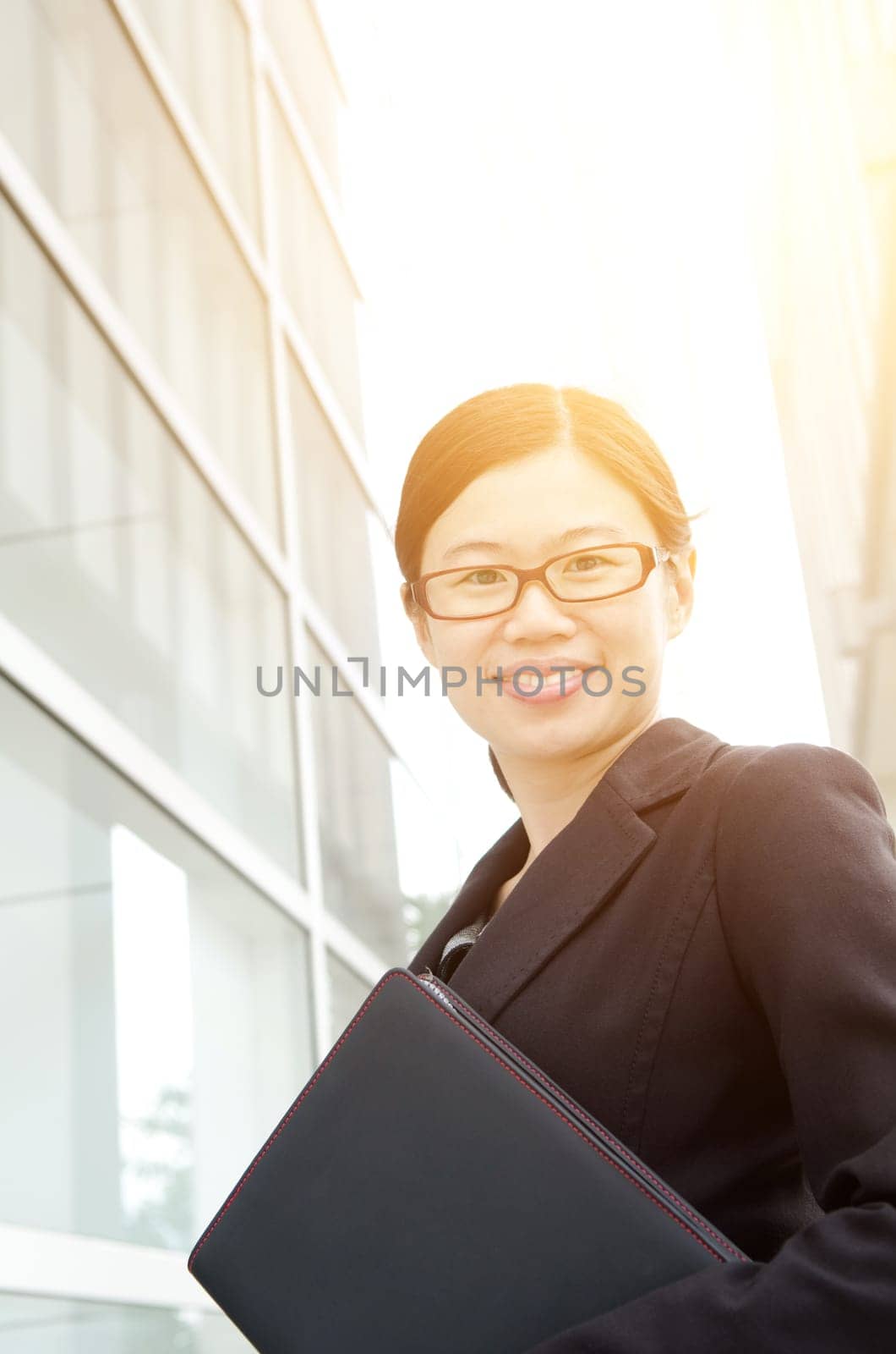 Asian executive smiles and standing outdoors