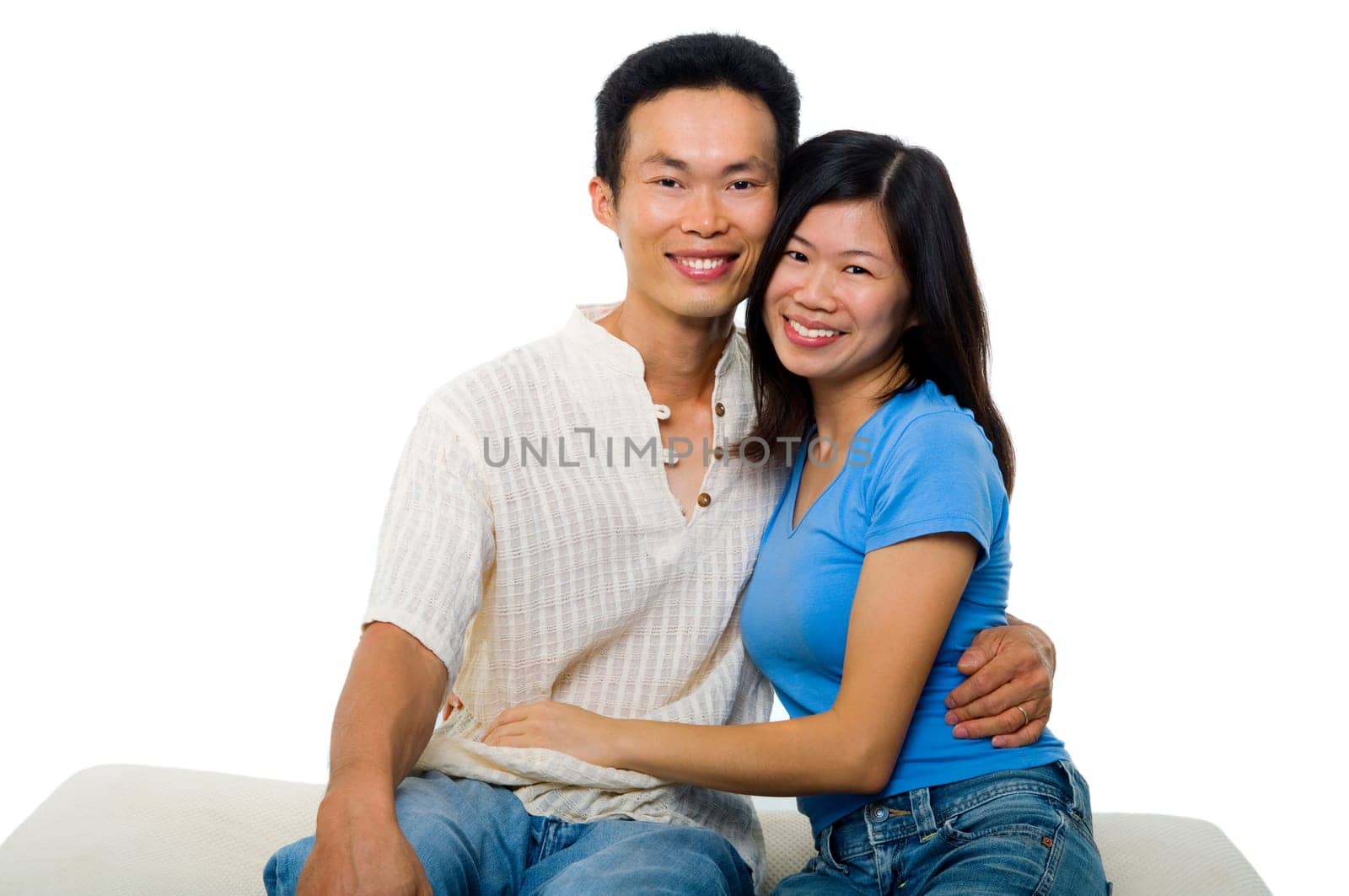Young Asian couple sitting on sofa with smiling face, on white background.