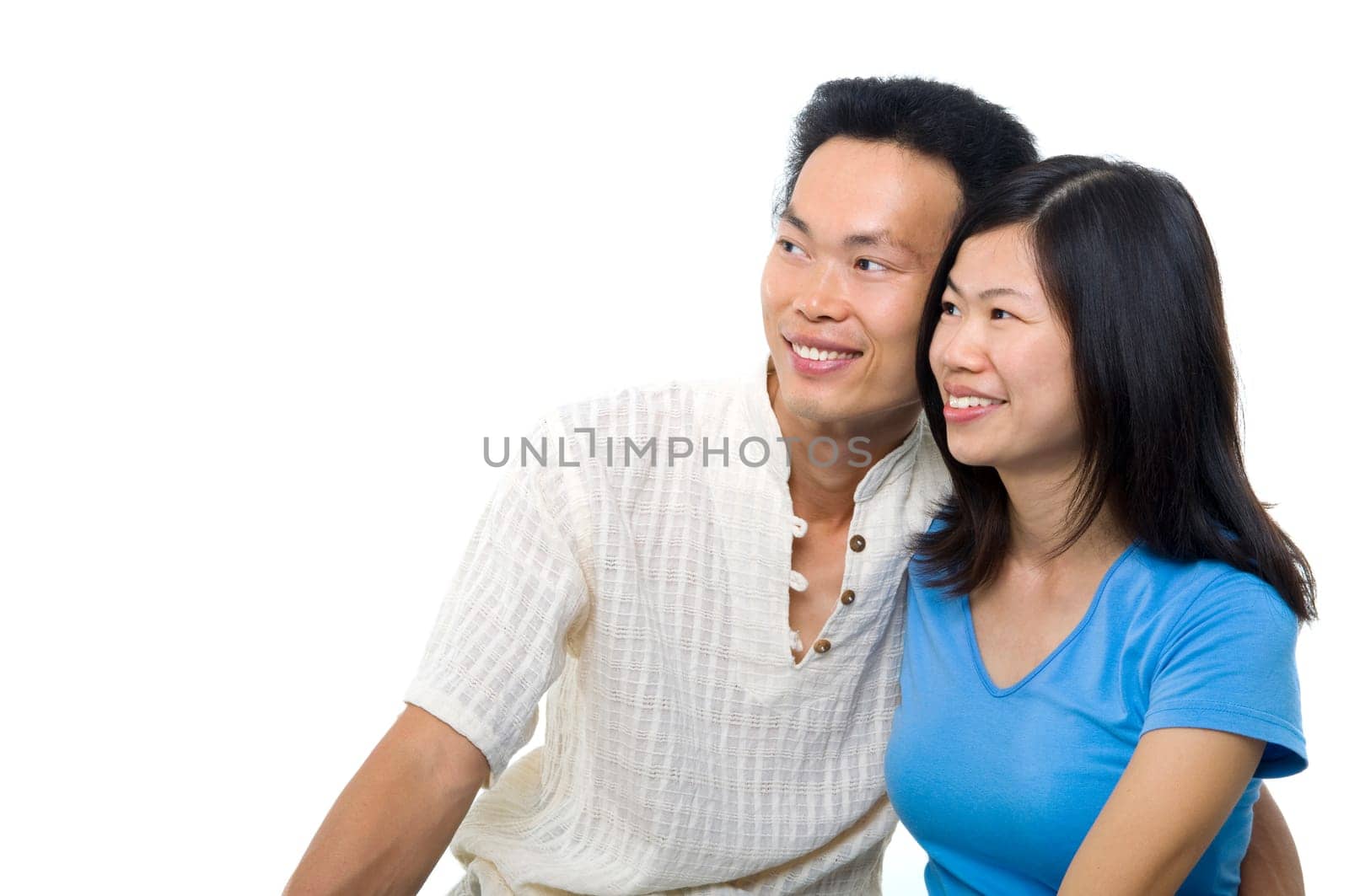 Young Asian couple sitting on sofa with smiling face, looking at side, on white background.