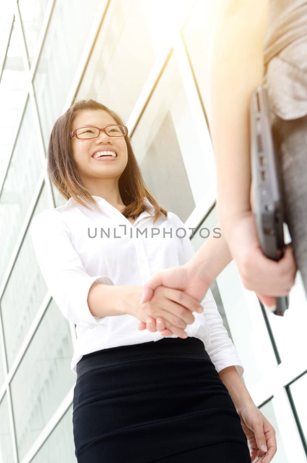 Asian office women hand shaking in front modern building