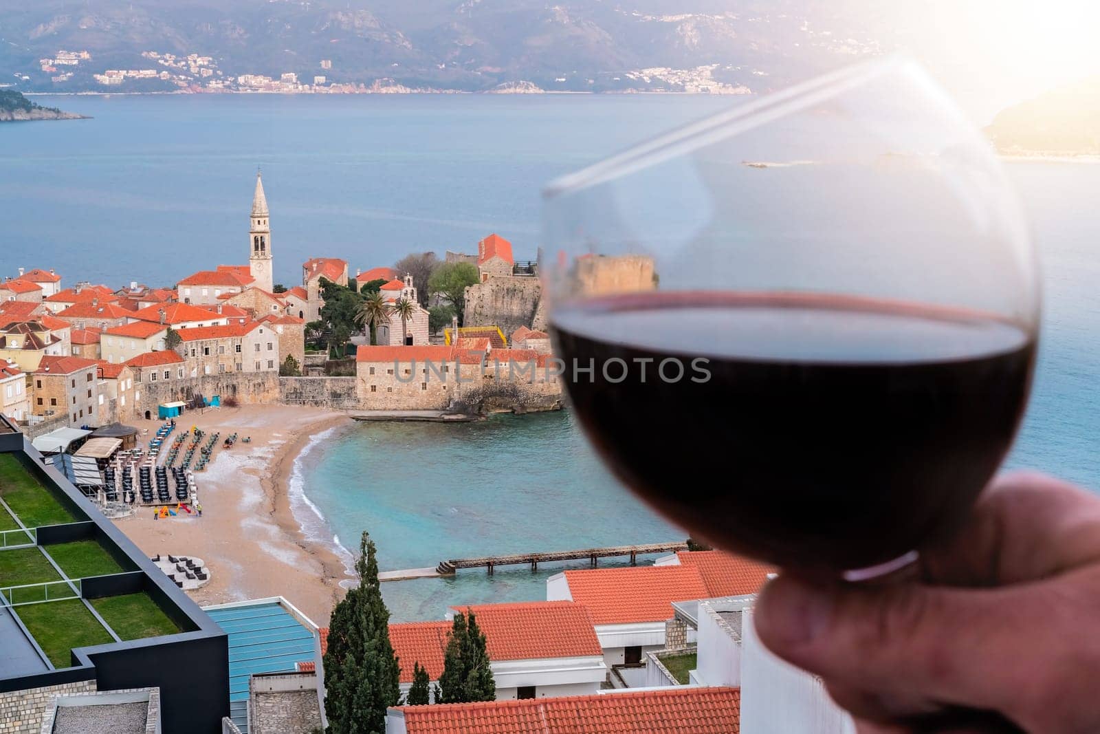 Woman holding glass with red wine on the balcony of her apartment in the Budva town, Montenegro