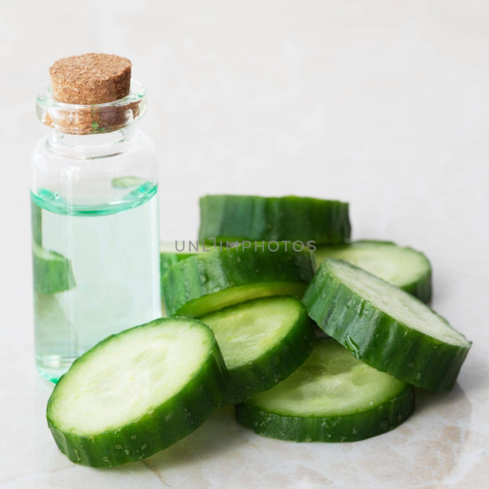 Small bottle of cucumber extract and cucumber slices for medicinal or cosmetic use.