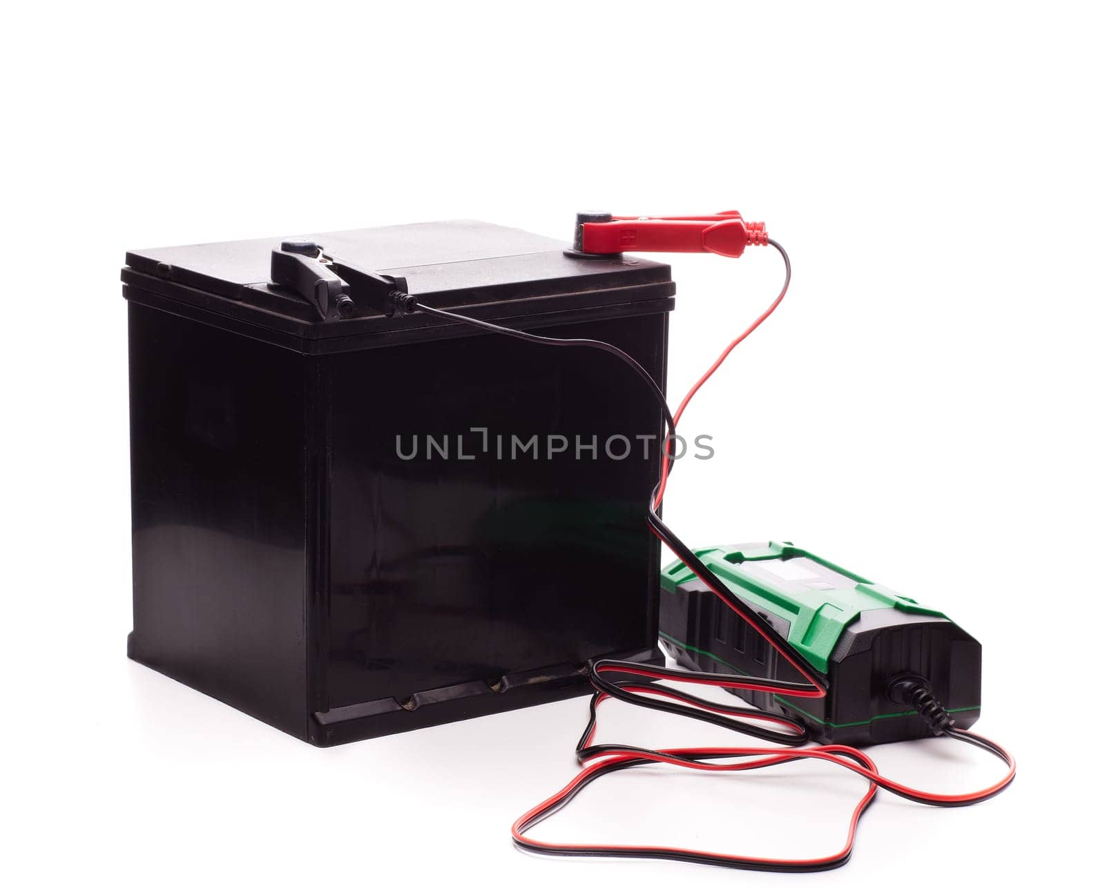 Black car accumulator battery and green charger isolated on a white background. Acid battery,12 volts supply. Concept of service, maintenance, charging car battery, diy
