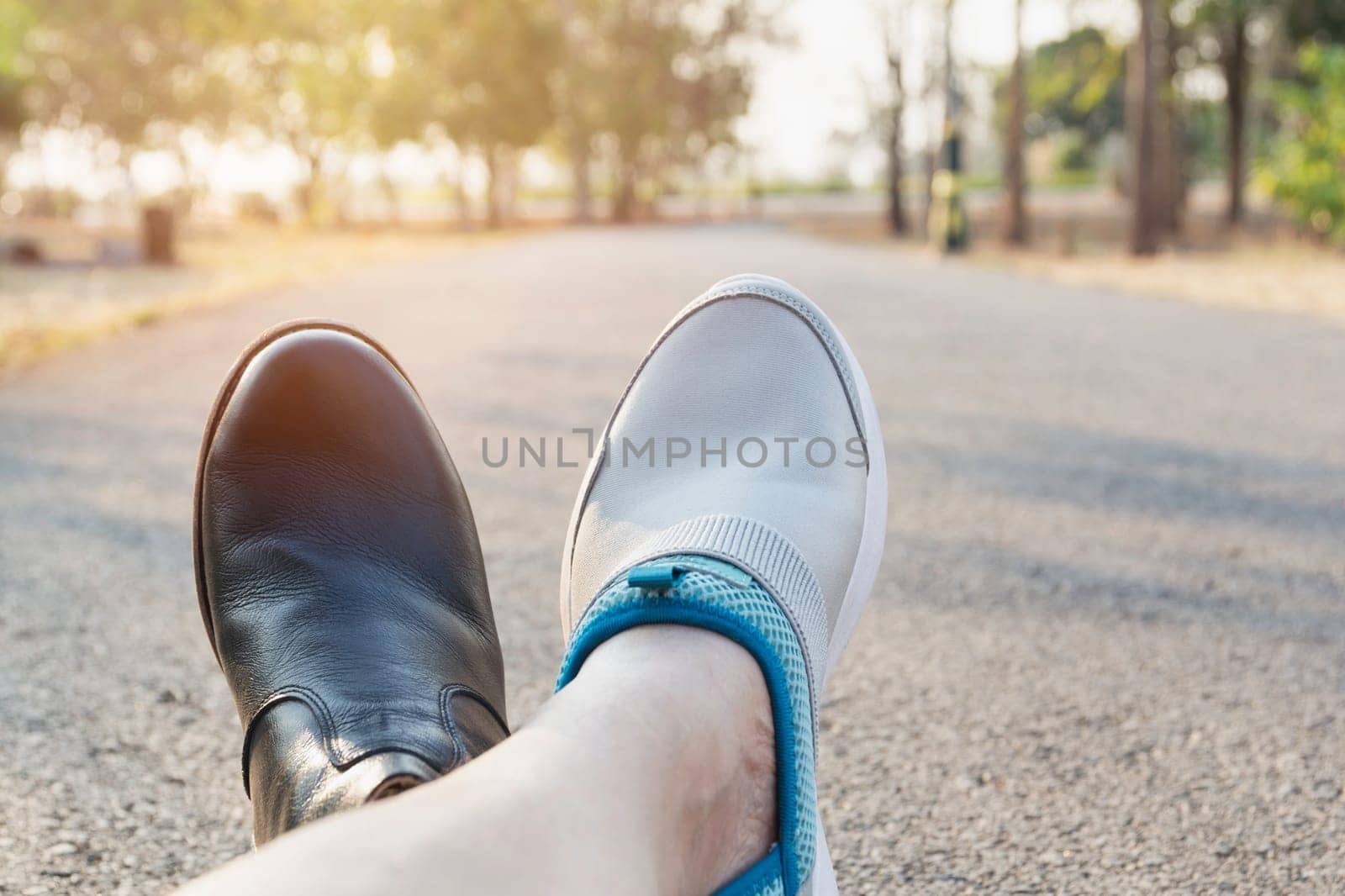 Feet of man wearing black and white shoes and sitting on the road with copy space.