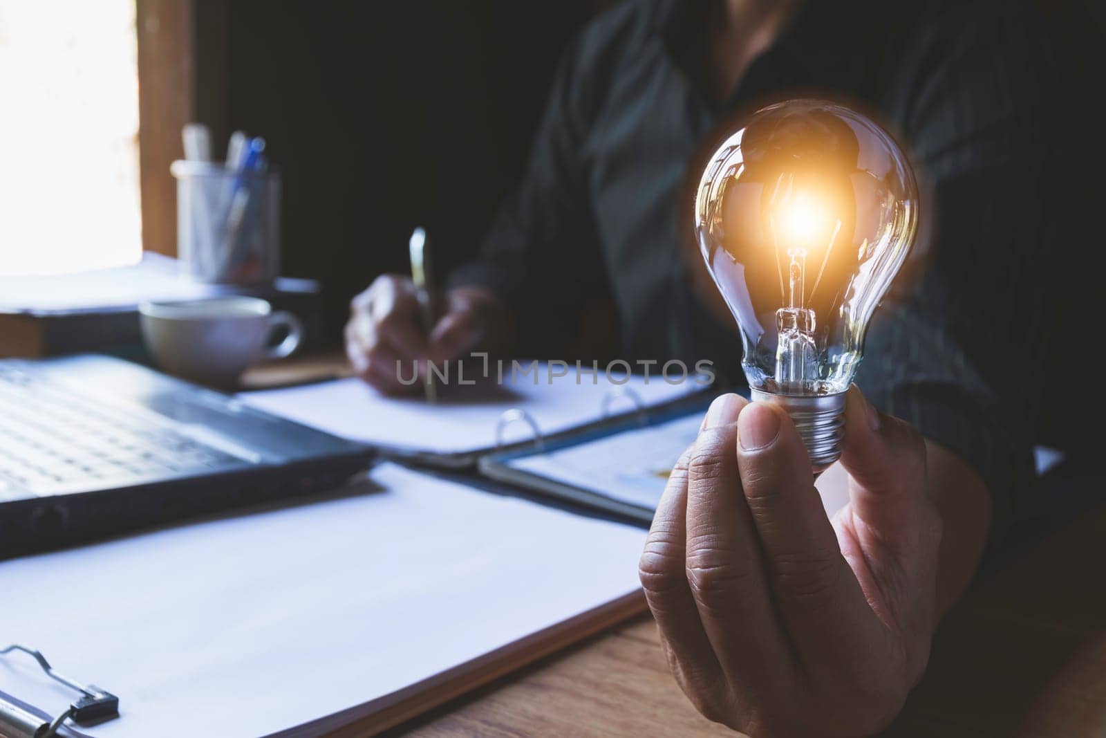 Hand of male holding a light bulb and writing for idea and creative concept.