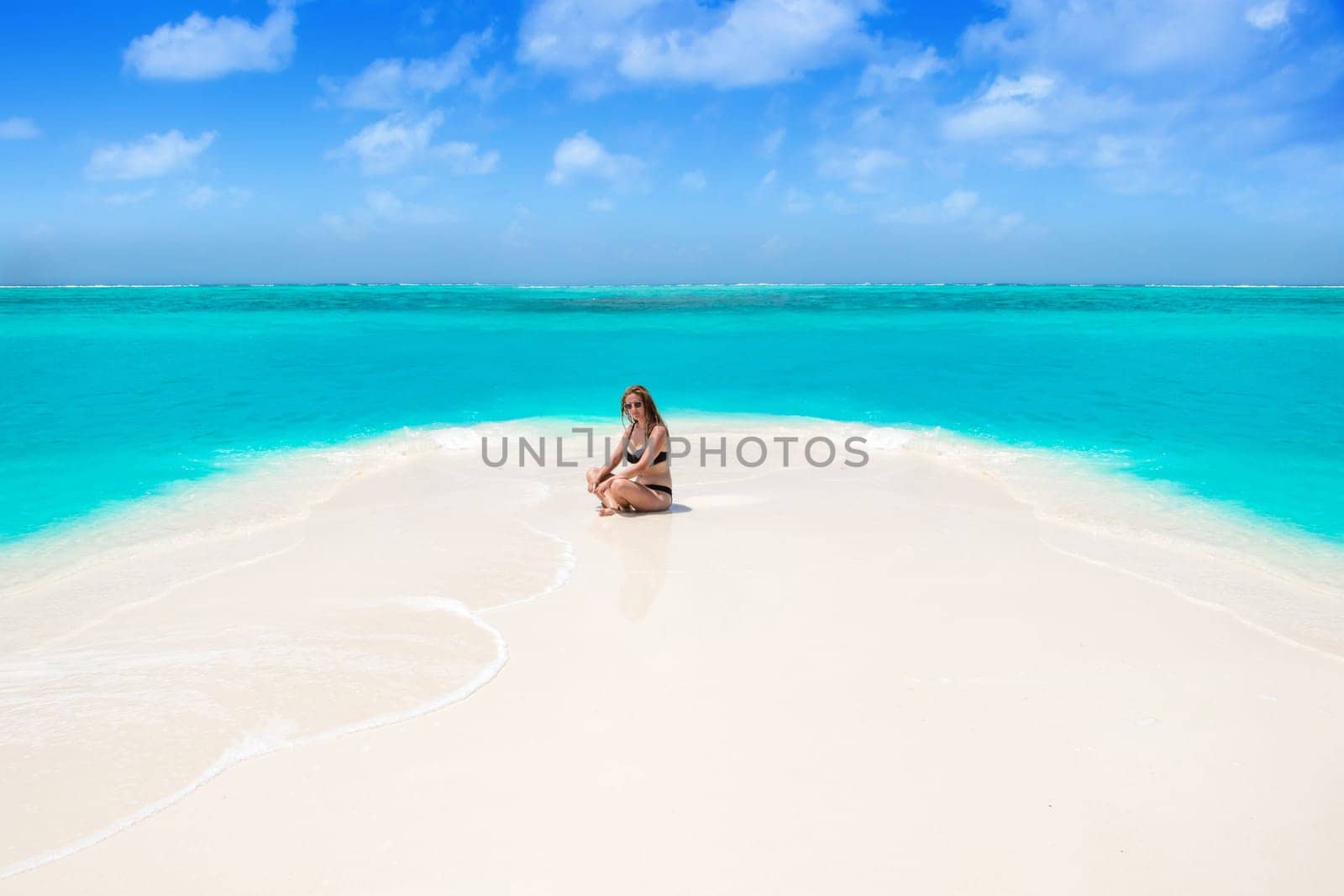Blonde Girl in black bikini on dream beach at the turquoise ocean