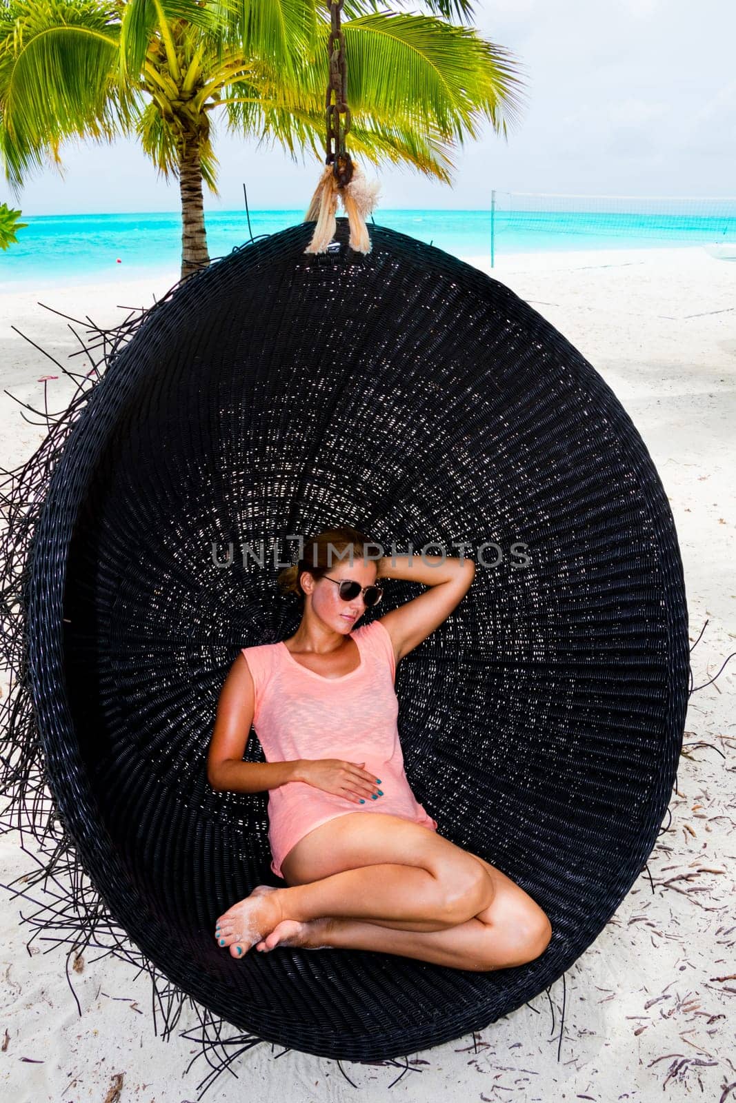 Beautiful woman relaxes on a swing on the dream beach