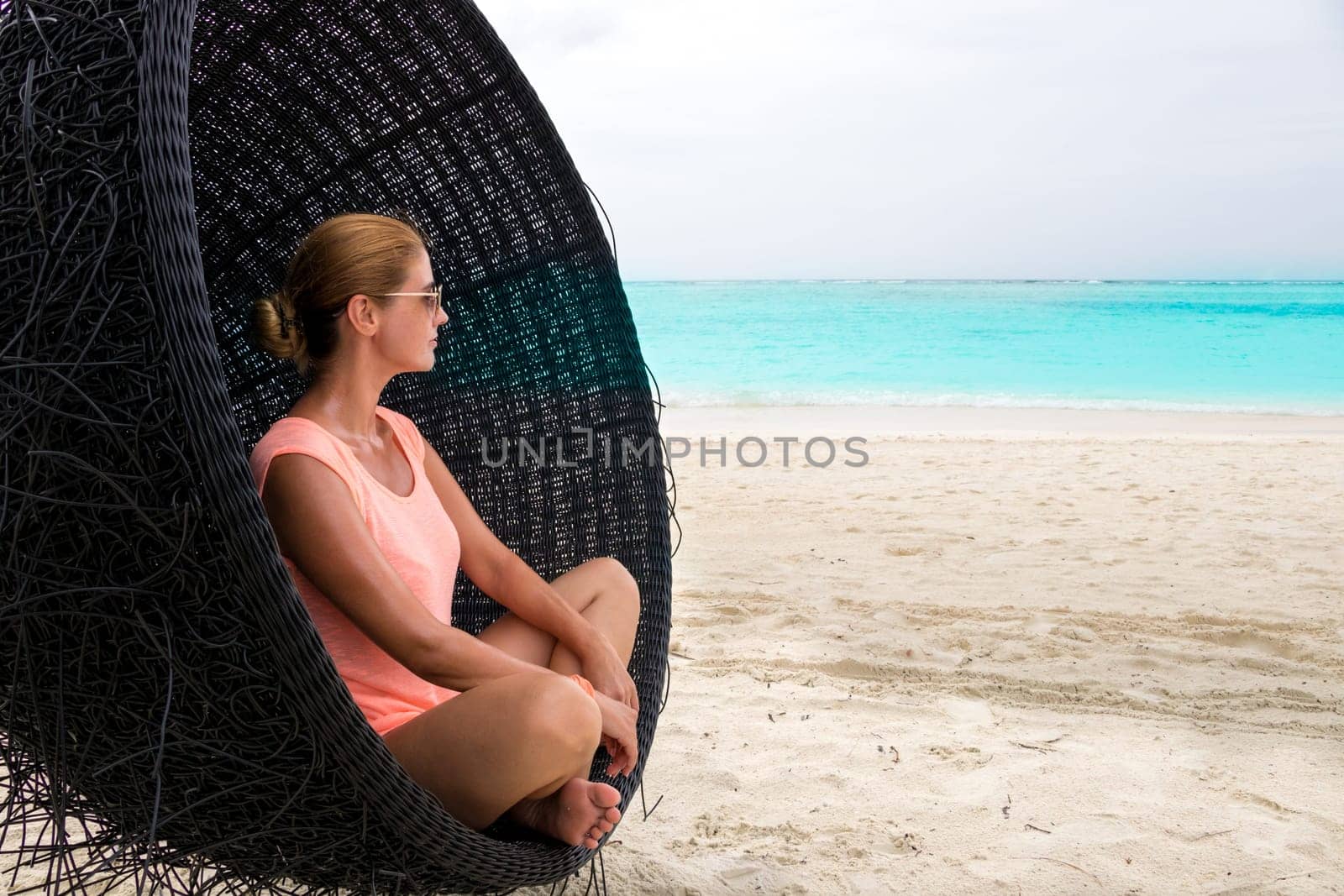 Beautiful woman relaxes on a swing on the dream beach